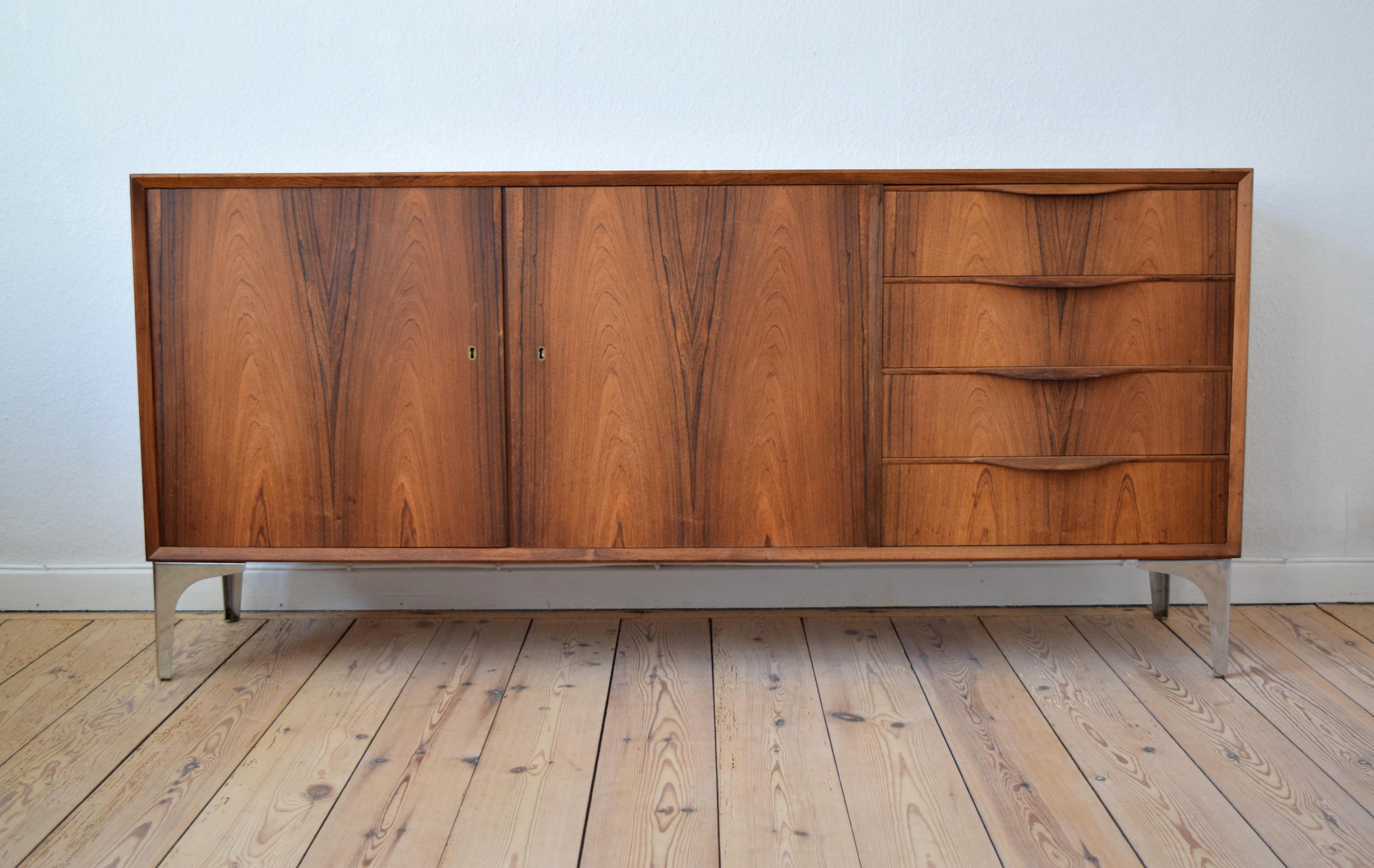 Low rosewood sideboard designed by Erling Torvits for Klim Møbelfabrik. This piece features four drawers with lipped handles, and two lockable doors (key included) with interior shelves. Contrasting teak and rosewood veneers used on the inside of