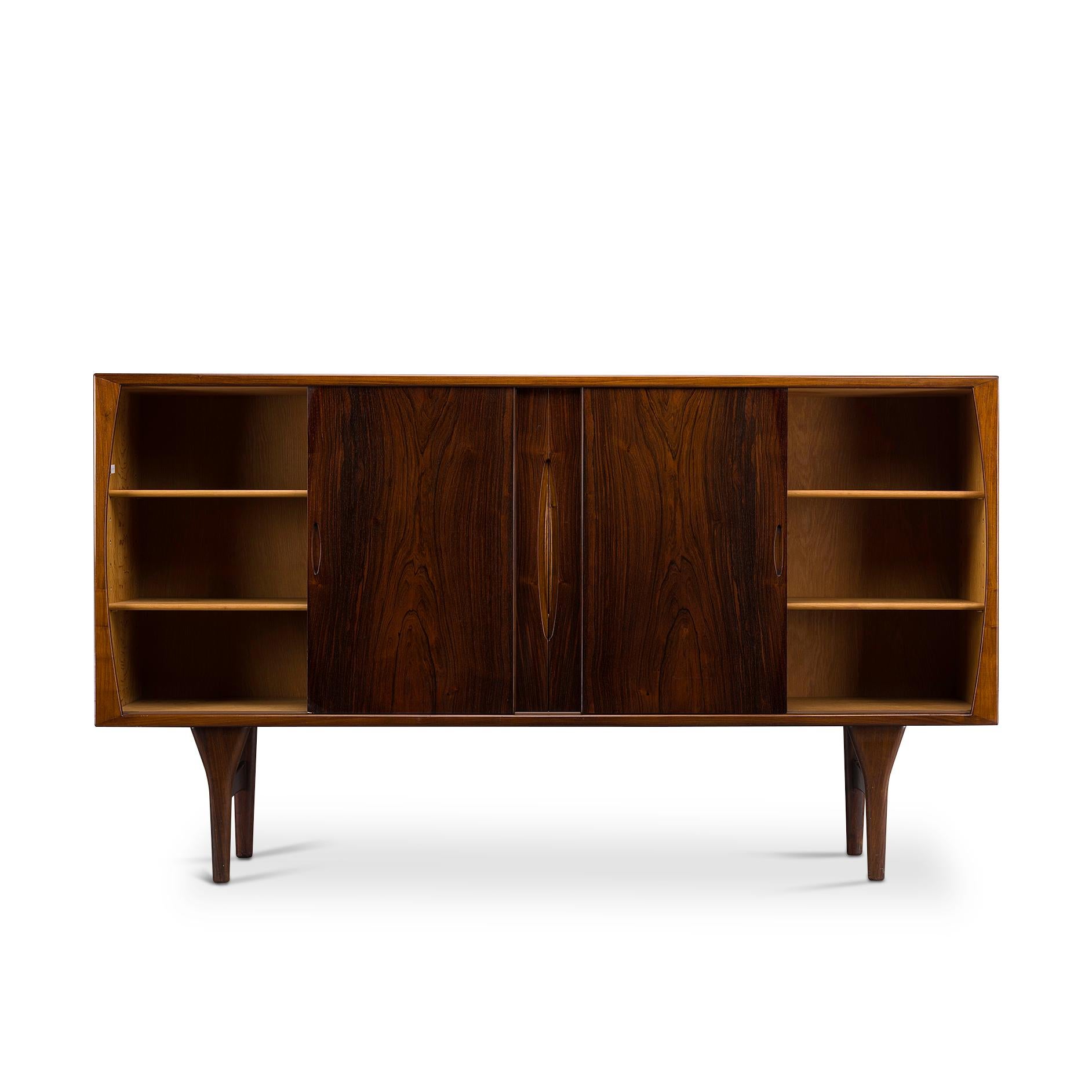 This Danish Mid-Century Modern credenza is a top-quality unit by Henning Kjaernulf for Bruno Hansen. Perfection in shape by subtle and well thought through detail. Like the solid wooden bezel, the carved grips in the sliding doors and the selection