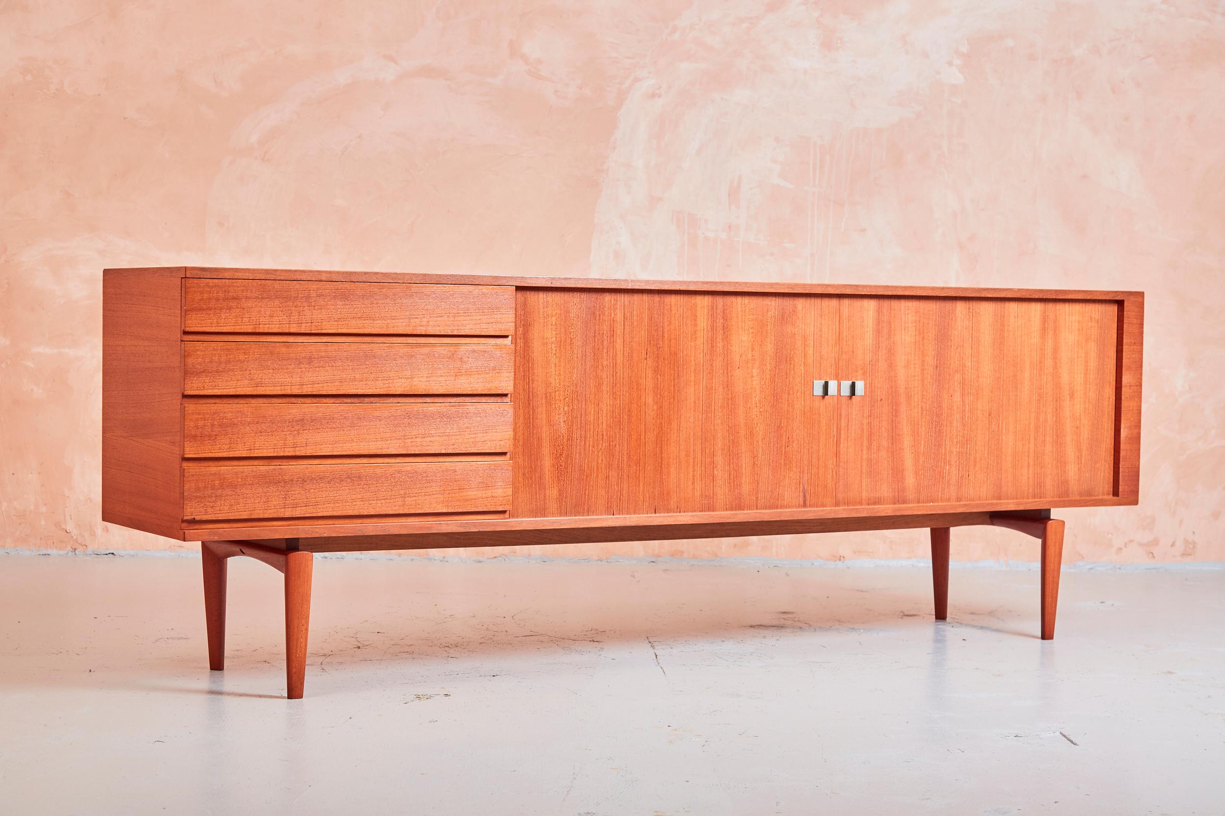 A sought after design classic, this sideboard was designed by Henry Walter Klein, and produced by Bramin in the 1960s.

With four drawers positioned next to two sliding tambour doors, the credenza shows exquisite craftsmanship and balanced