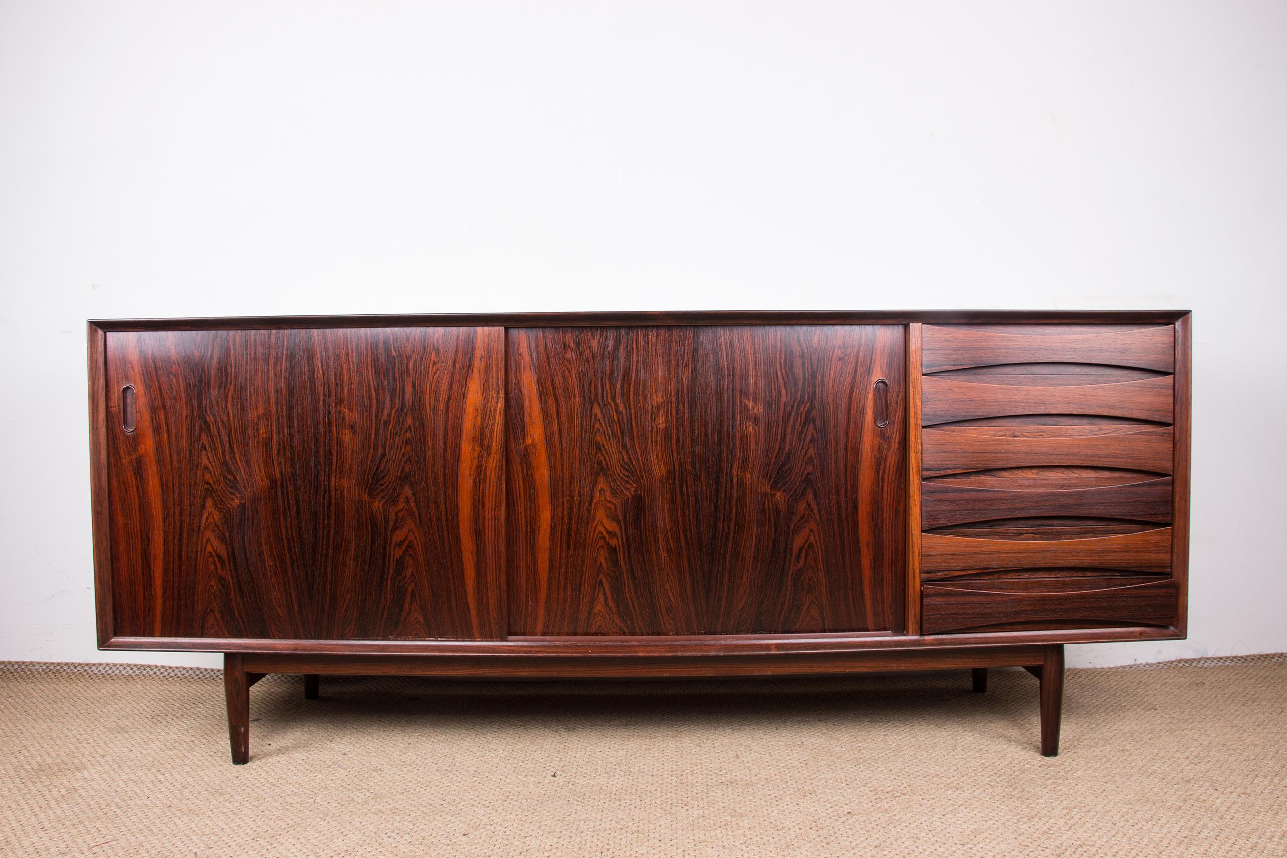 Superb Scandinavian sideboard. 
The 2 sliding doors on the left are reversible, either in rosewood or in pastel colors. 
6 drawers on the right side. 
The rosewood is dark and gives this piece of furniture a rare elegance. 
This is an iconic model