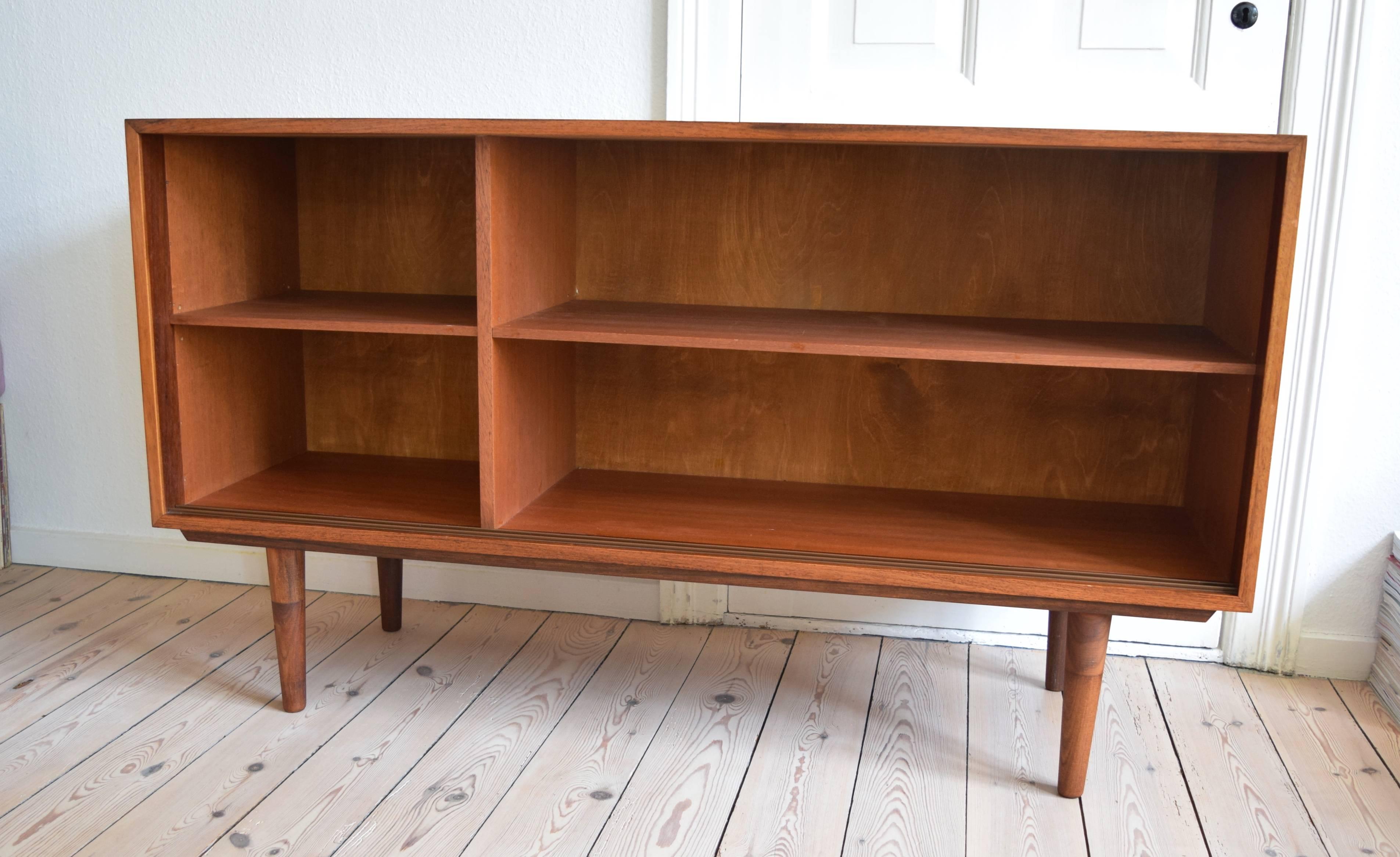 Low rosewood sideboard manufactured by Viby Møbler in Denmark in the 1960s. This piece features two sliding doors with solid rosewood handles and teak veneer shelves. Sits on turned and tapered two-tone teak legs. Stunning wood grain throughout this