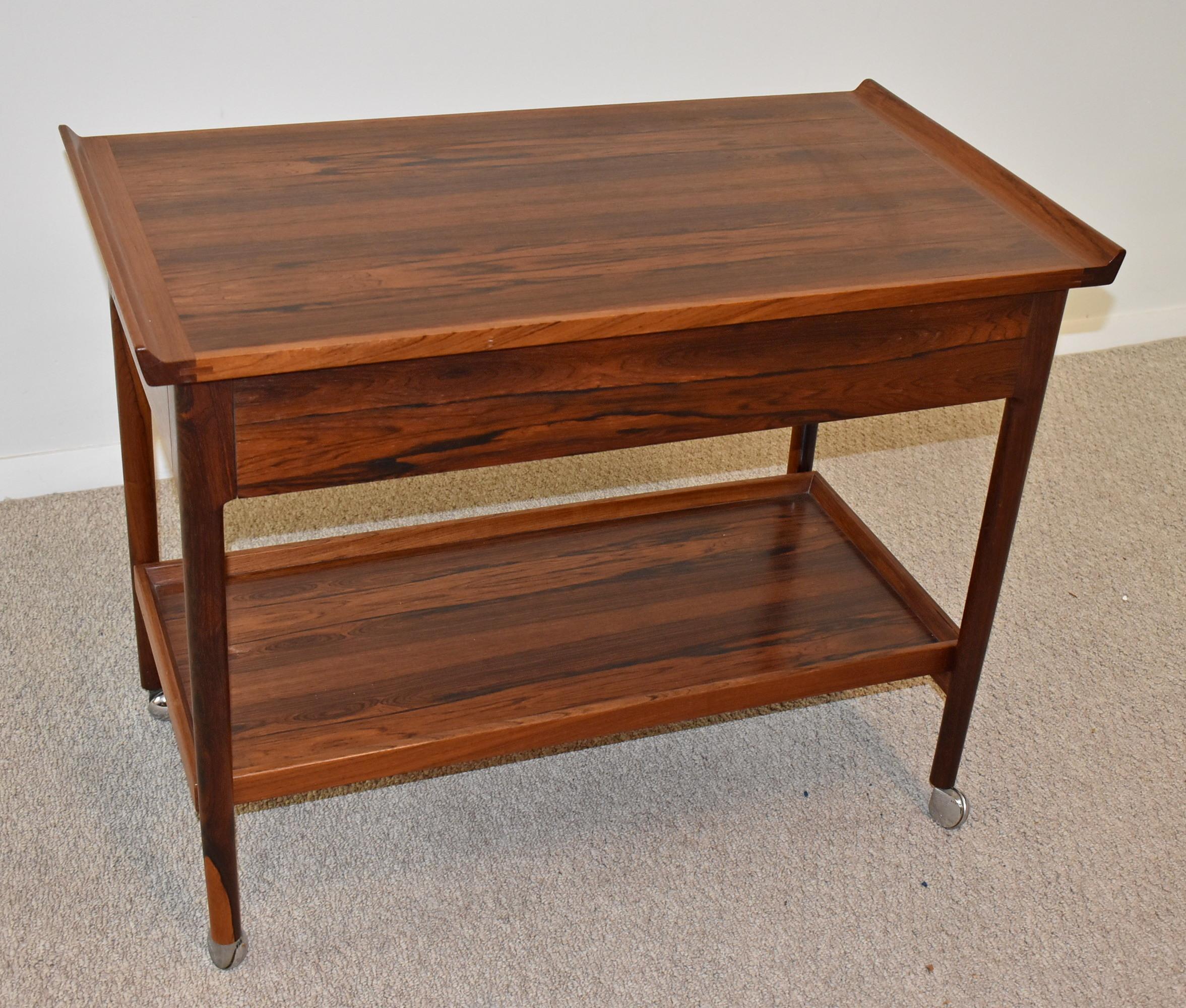 Danish Rosewood Trolley Bar Cart by Torbjorn Afdal (Designer) for Mellemstrands Bruksbo (Maker). Circa 1960-1969. Mid-Century Modern double drawer rosewood bar cart, contoured handles and turned legs with lower tray that acts as a shelf. Well