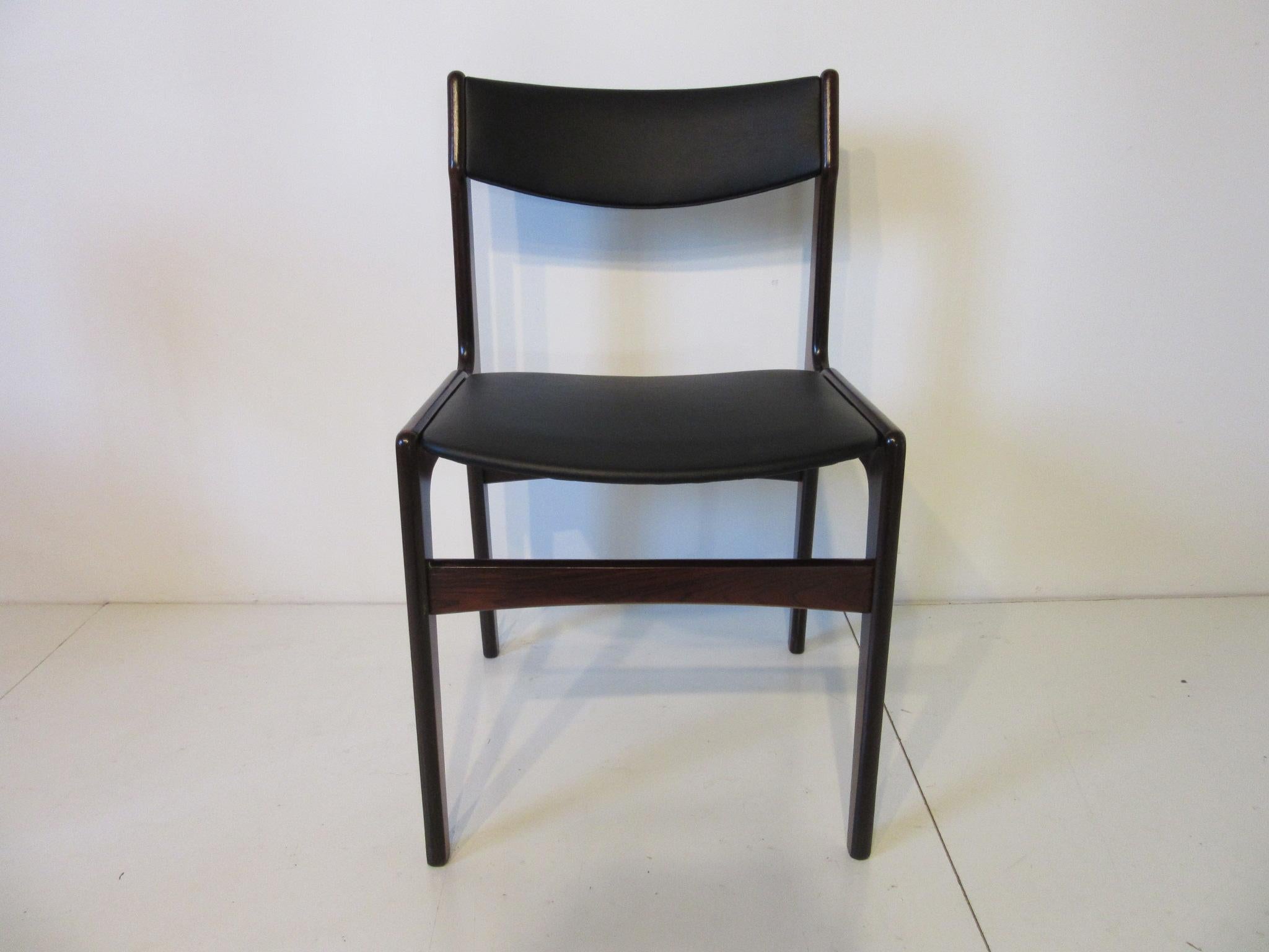 A set of four Brazilian rosewood framed Danish dining chairs reupholstered in a soft black leatherette in the manner of Erik Buck. A rich mix of rosewood and satin black fabric that makes these so perfect for that warm dining space .