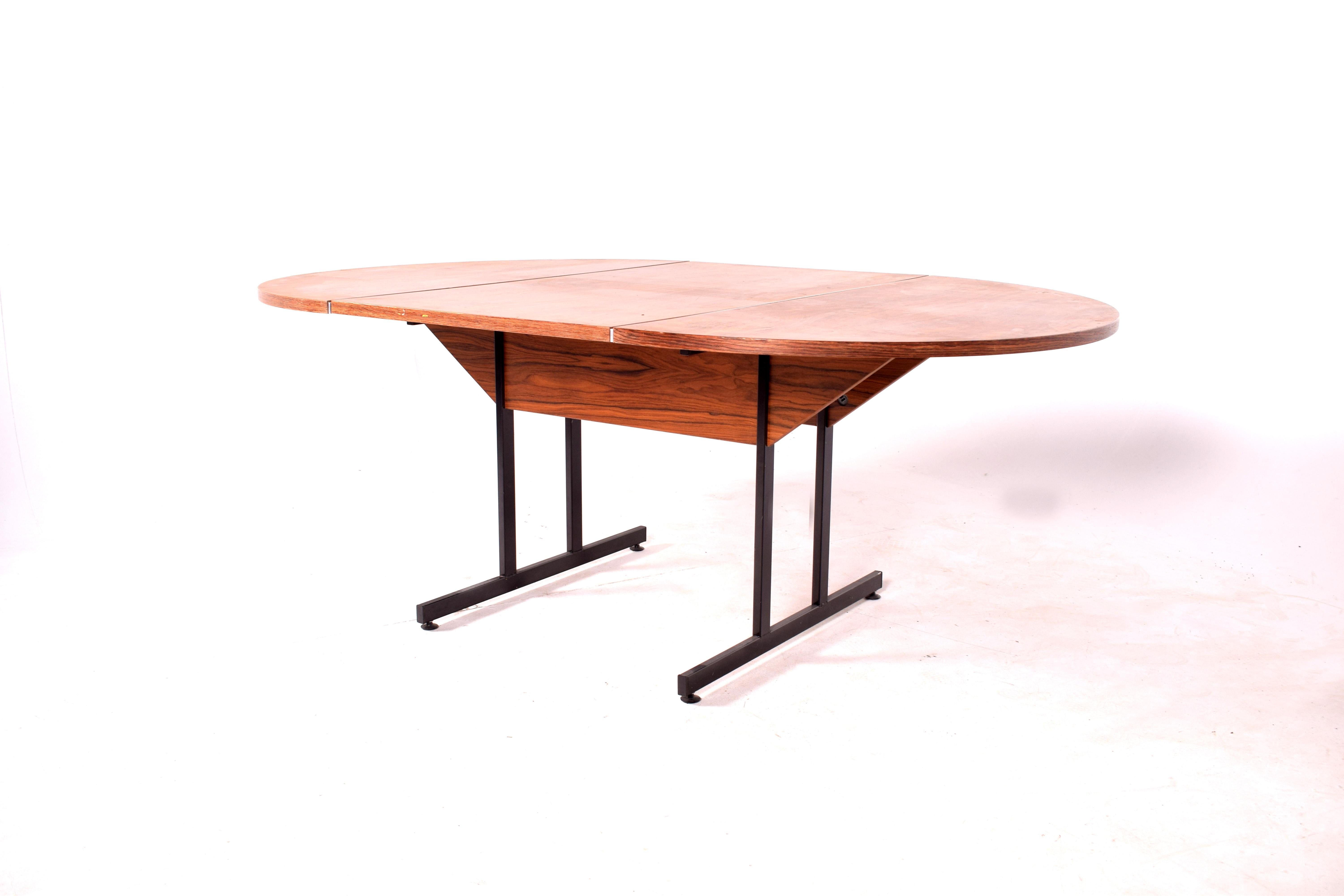Rare oval dining or work table, made of rosewood veneer with a central foot in wood and metal. It has two aluminum applications on the top, which gives it a modern and different look.