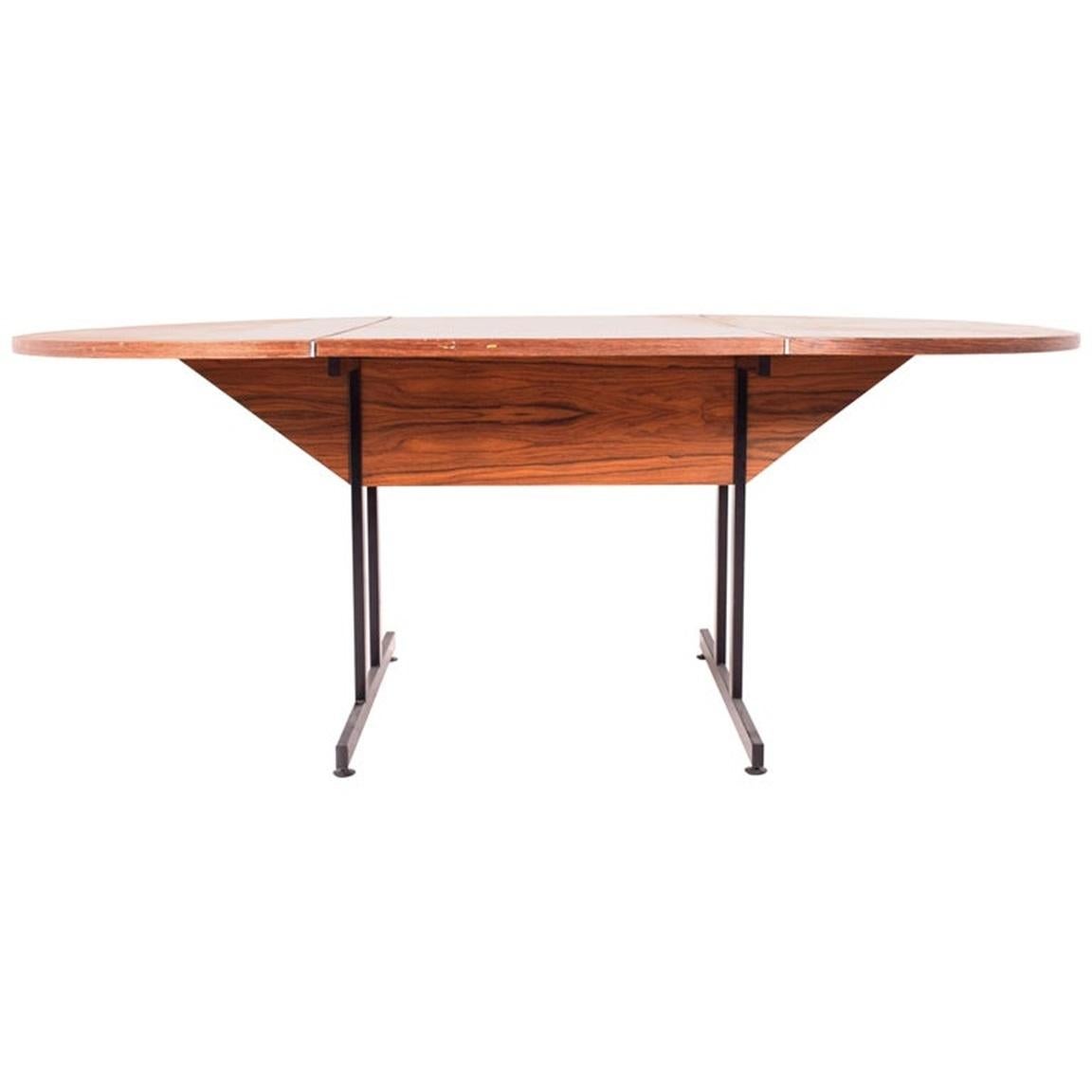 Cette table de salle à manger ou de travail moderne du milieu du siècle est dotée d'un plateau en palissandre épuré, mettant en valeur le grain naturel et la beauté du bois. Sa forme ovale offre un design fonctionnel et élégant, parfait pour les