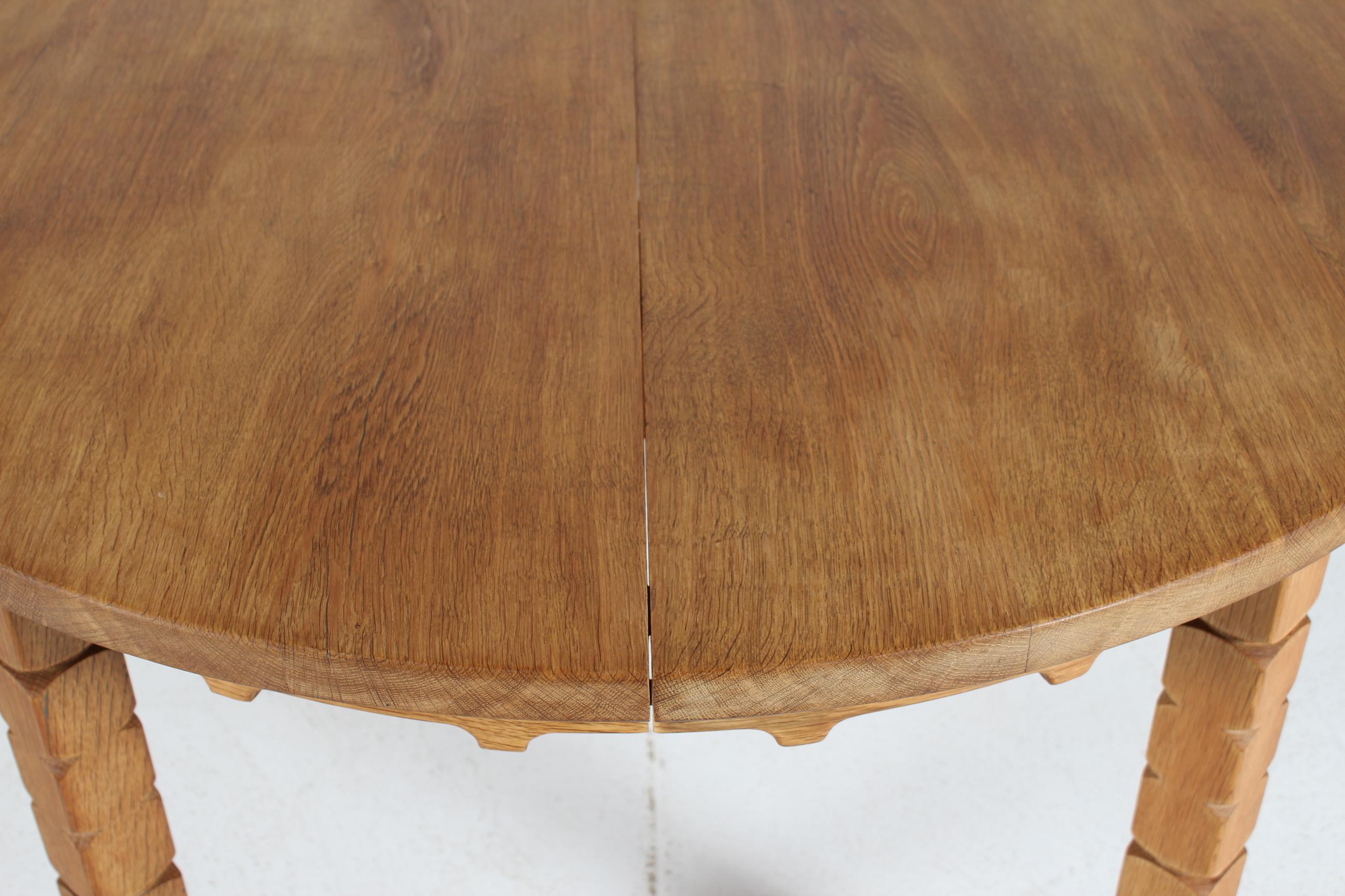 Danish vintage brutalist Henning Kjærnulf style round extendable dining table manufactured in Denmark in the 1970s.

The table is made of solid patinated oak with wood work details. 
It can be extended with three extra leaves of oak veneer. 

The