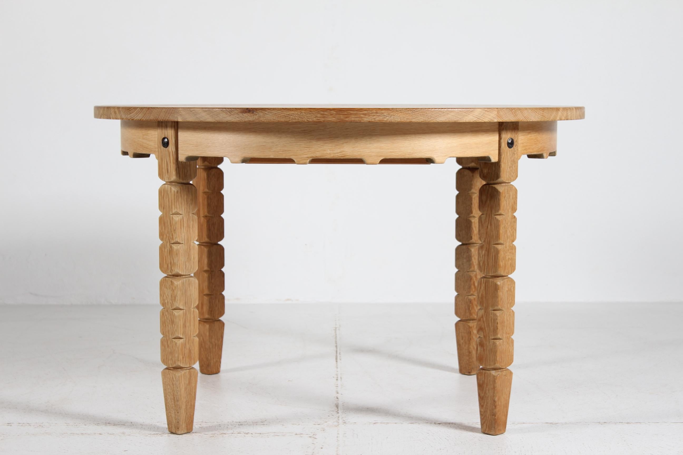 Danish vintage Henning Kjærnulf style round extendable dining table manufactured in Denmark in the 1970s.

The table is made of solid patinated oak with wood work details. 
It can be extended with three extra leaves of oak veneer. One of the leaves