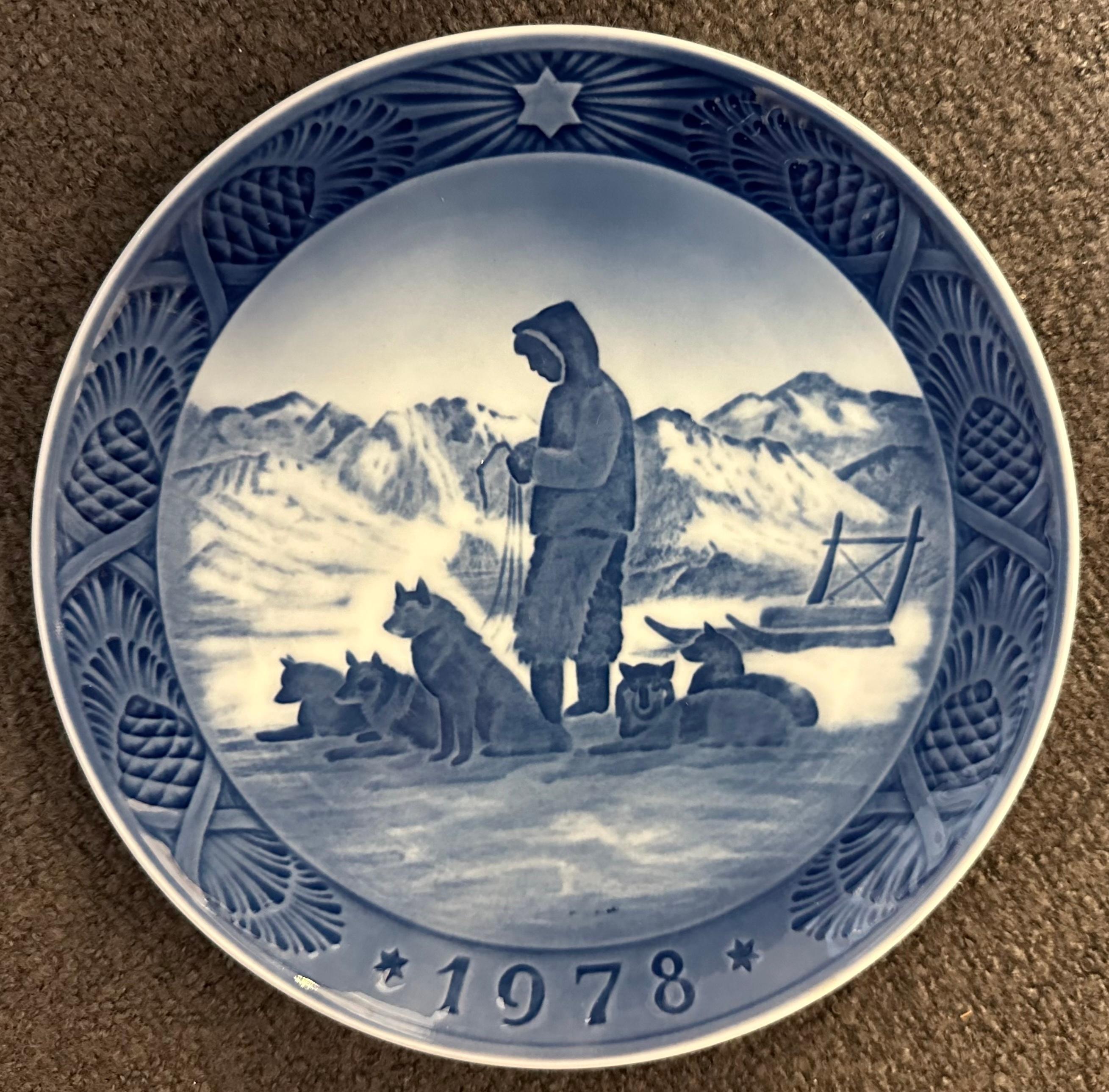 Royal Copenhagen 1978 Christmas Plate - Greenland Scenery designed by Kai Lange. The scene on this year's Christmas Plate depicts a set of sled of five dogs possibly huskies and their young owner standing with their head facing downwards perhaps