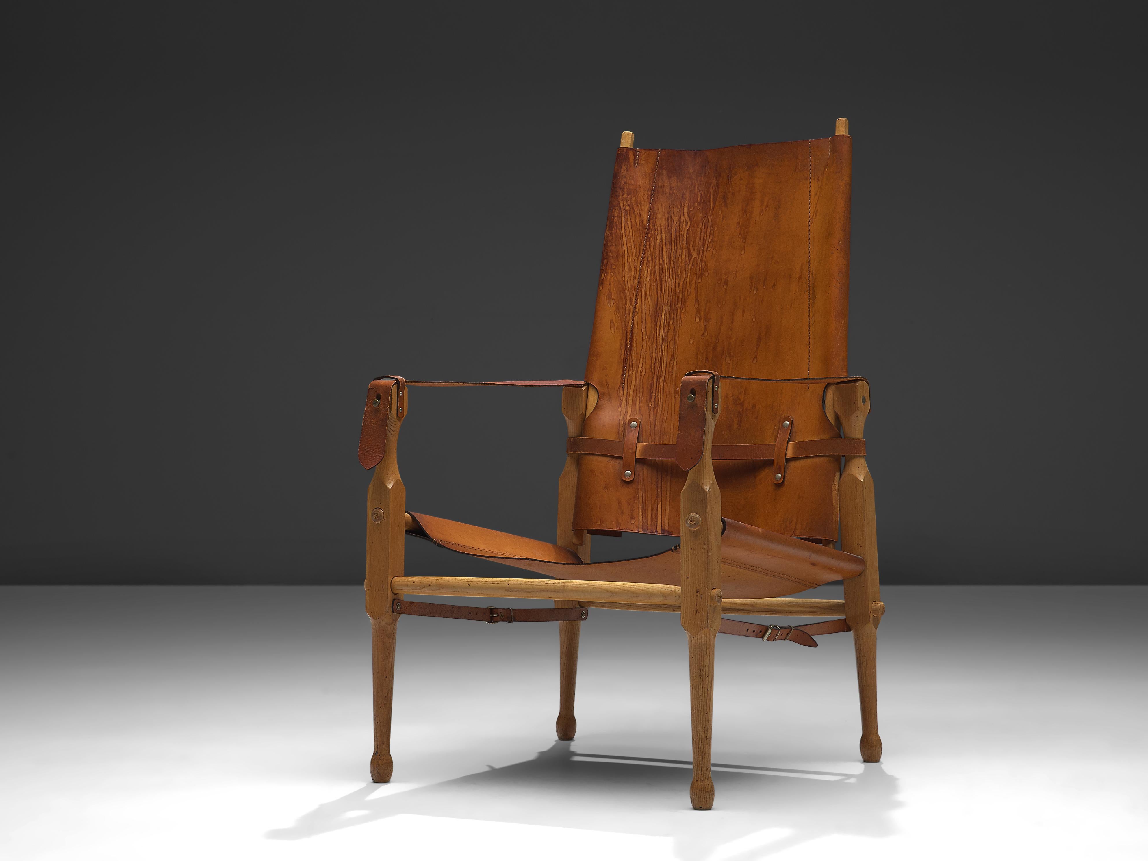 Lounge chair, leather, ash, brass, Denmark, 1960s 

This Danish 'Safari' armchair shows very elegant and well-designed lines, in combination with carefully crafted wood joints. The patinated cognac leather with multiple straps completes this chair's