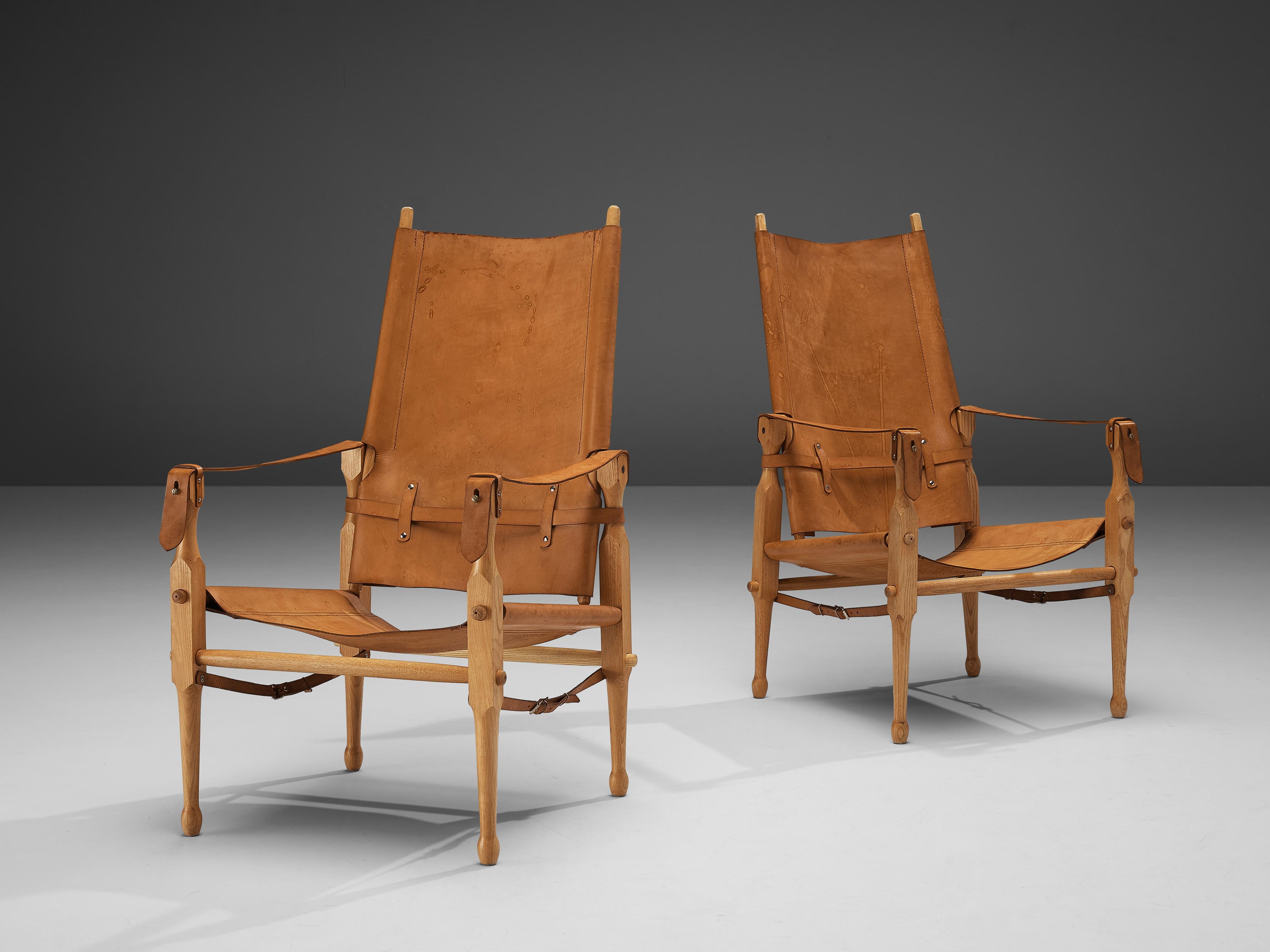 Lounge chairs, leather, beech, brass, Denmark, 1960s 

These Danish 'Safari' armchairs show very elegant and well-designed lines, in combination with carefully crafted wood joints. The patinated cognac leather with multiple straps completes this