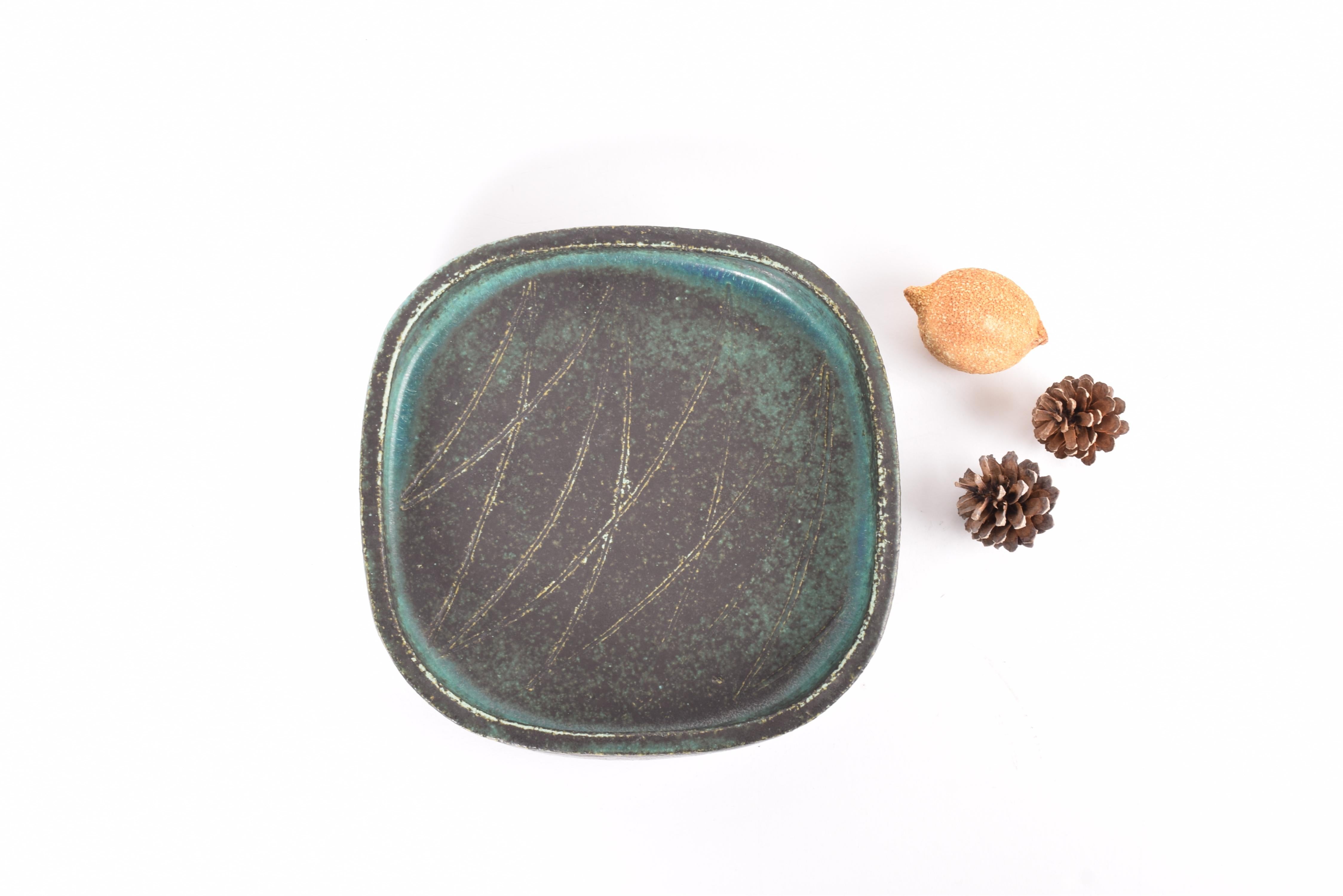 Vassoio quadrato vintage di Eva Stæhr Nielsen per il leggendario laboratorio di ceramica Saxbo. Realizzato circa negli anni '60 o '70. Anni '60 o '70.

Il vassoio ha uno stile rustico decorato con linee incise e un'interessante smaltatura in grigio