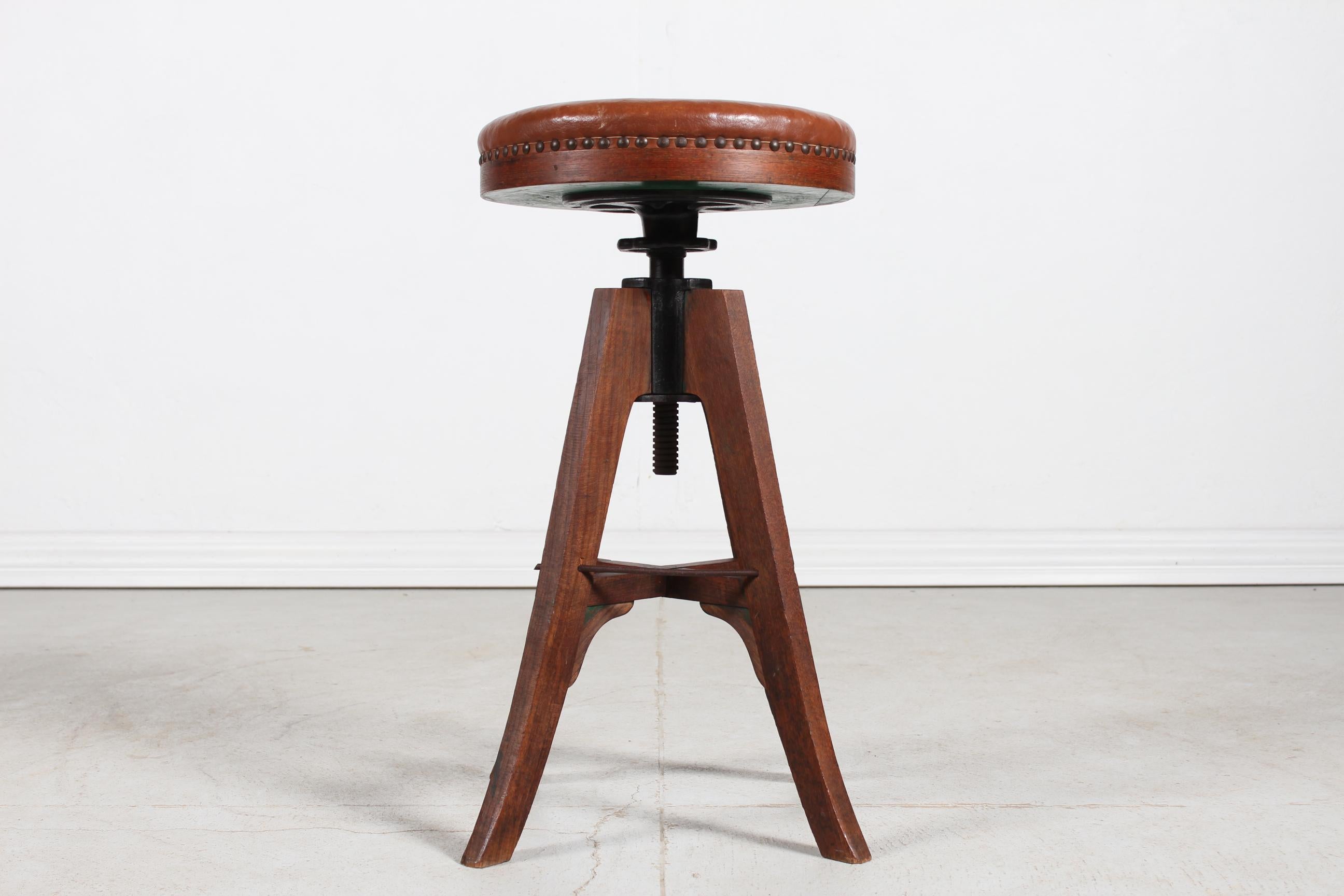 Danish tripod adjustable bar stool/desk stool/swivel stool made of solid oak with round seat mounted with cognac coloured leather with brass nails.
Made ca 1920s by a Danish cabinetmaker (Fritz Hansen)
It's possible to adjust the height of the chair