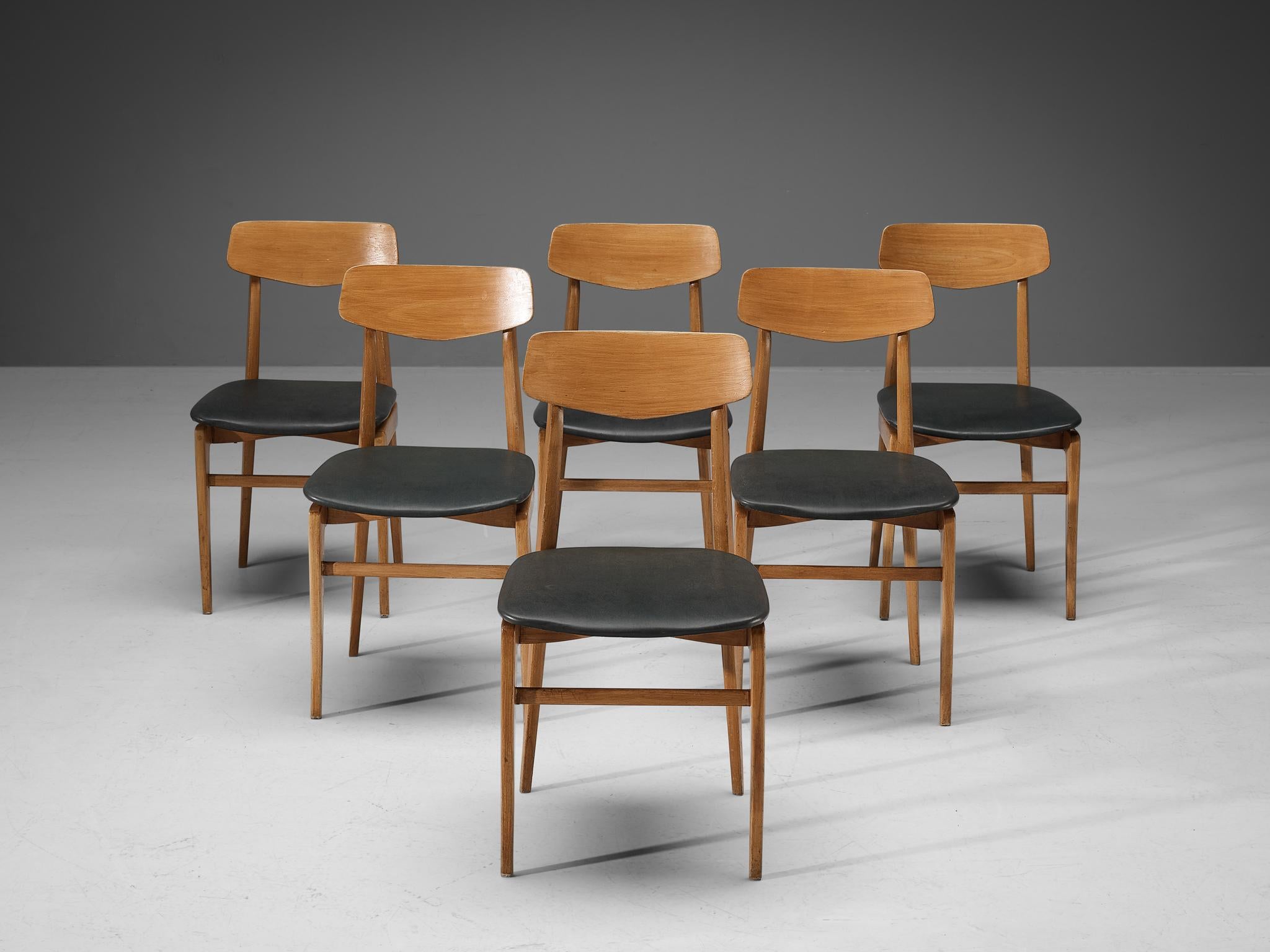 Set of six dining chairs, beech, faux leather, Denmark, 1960s. 

Modest and elegant set of six dining chairs. Its design shows clear lines and an open backrest. The dark grey leatherette seats give a striking contrast with the warm color of the