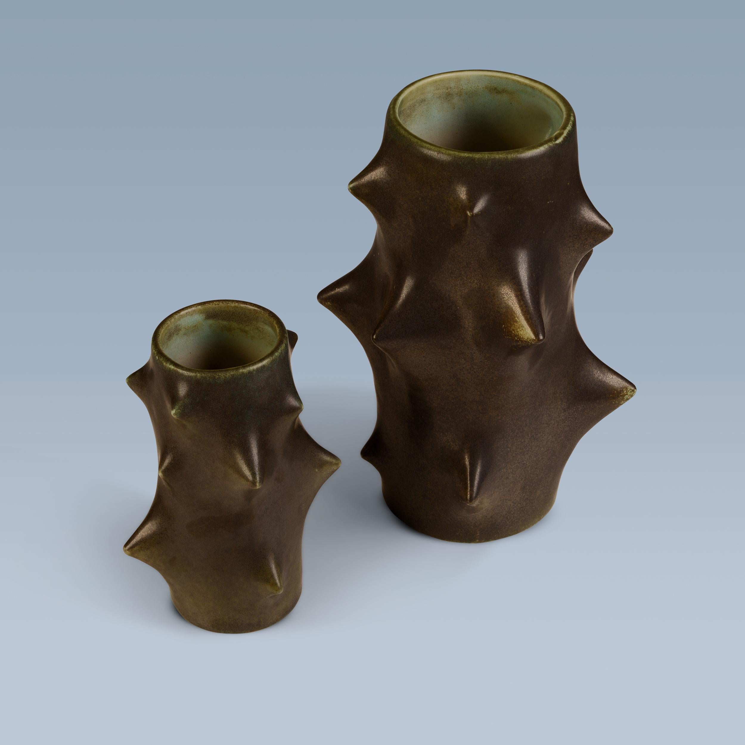 This set of two ‘Rosentorn’ / rose thorn vases are designed by Knud Basse (1916-1991). They have a cactus-like shape and are decorated with dark-greenish glaze.

Made and marked by Michael Andersen & Son, Bornholm. Denmark.

Signed with artist