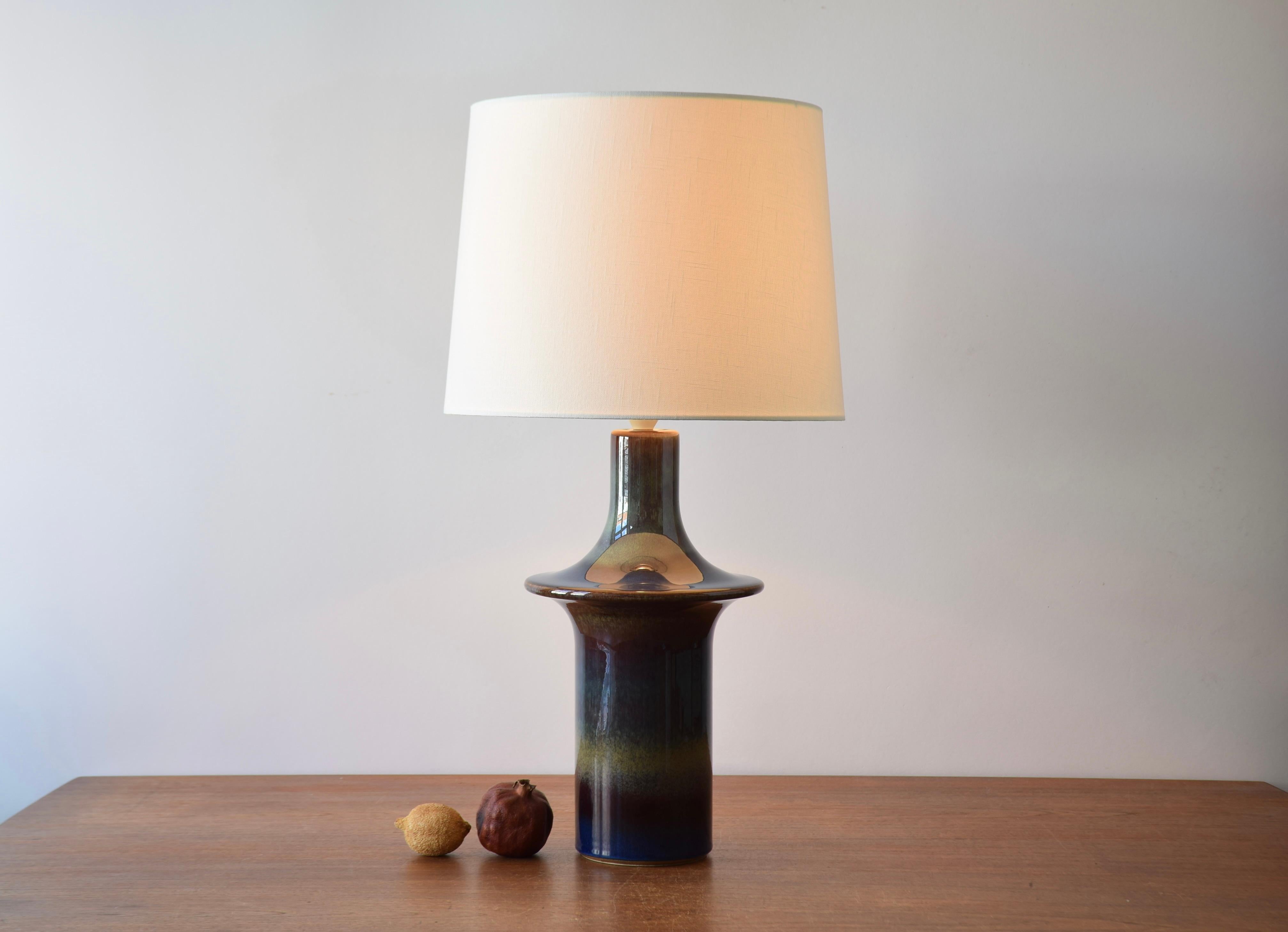 Danish Modern sculptural ufo shaped table lamp made by Søholm Stentøj The design is attributed to Einar Johansen. Made ca 1960s.

The lamp is decorated with glossy glaze with a beautiful color play in dark blue purple, yellow and brown and reminds