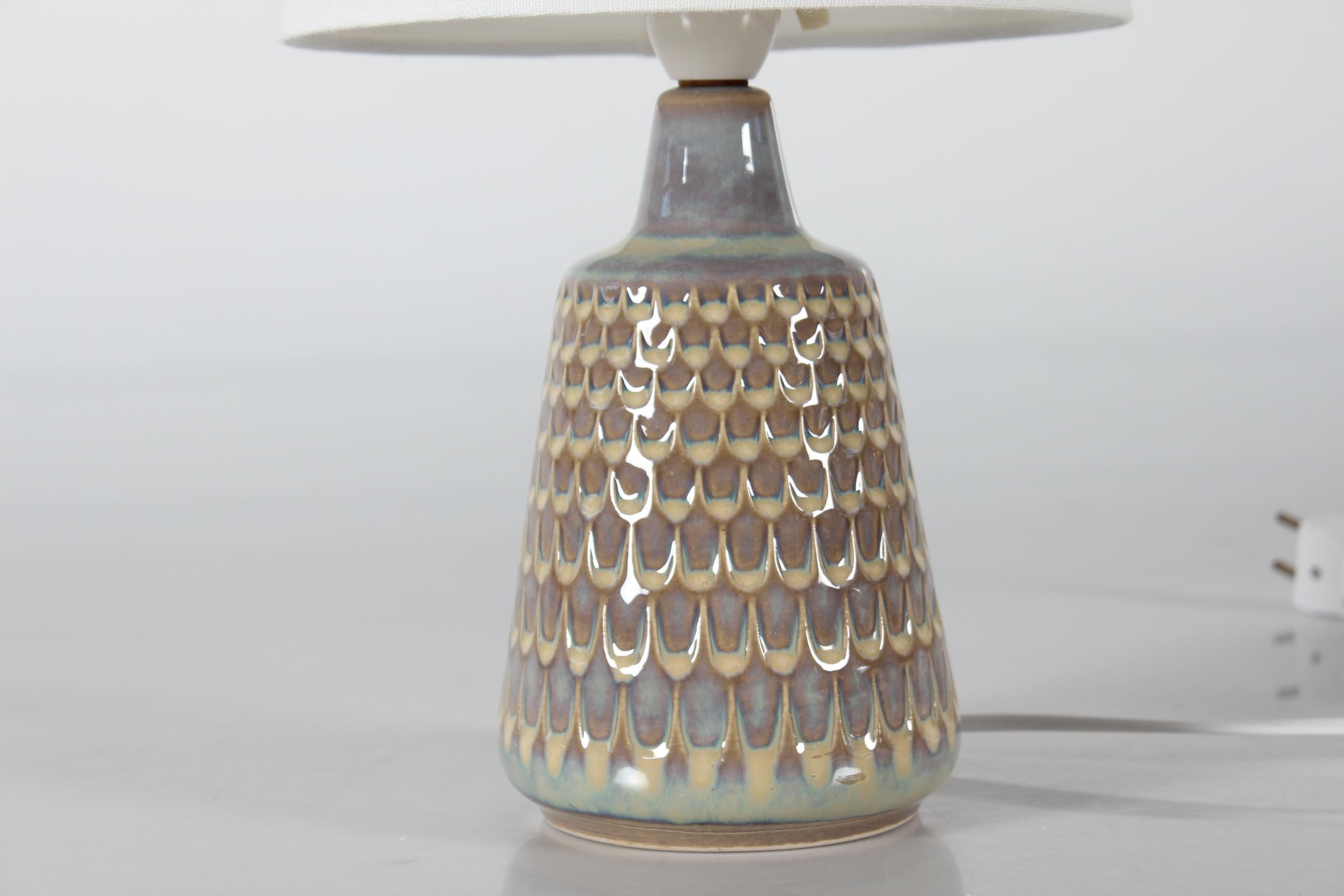 Small stoneware table lamp in Einar Johansen style made for Søholm Stentøj, Denmark, circa 1960s.
The lamp is decorated with a glossy dusty sand yellow and dusty lilac colored glaze turning into turquoise over a pattern in style of fish scales

The