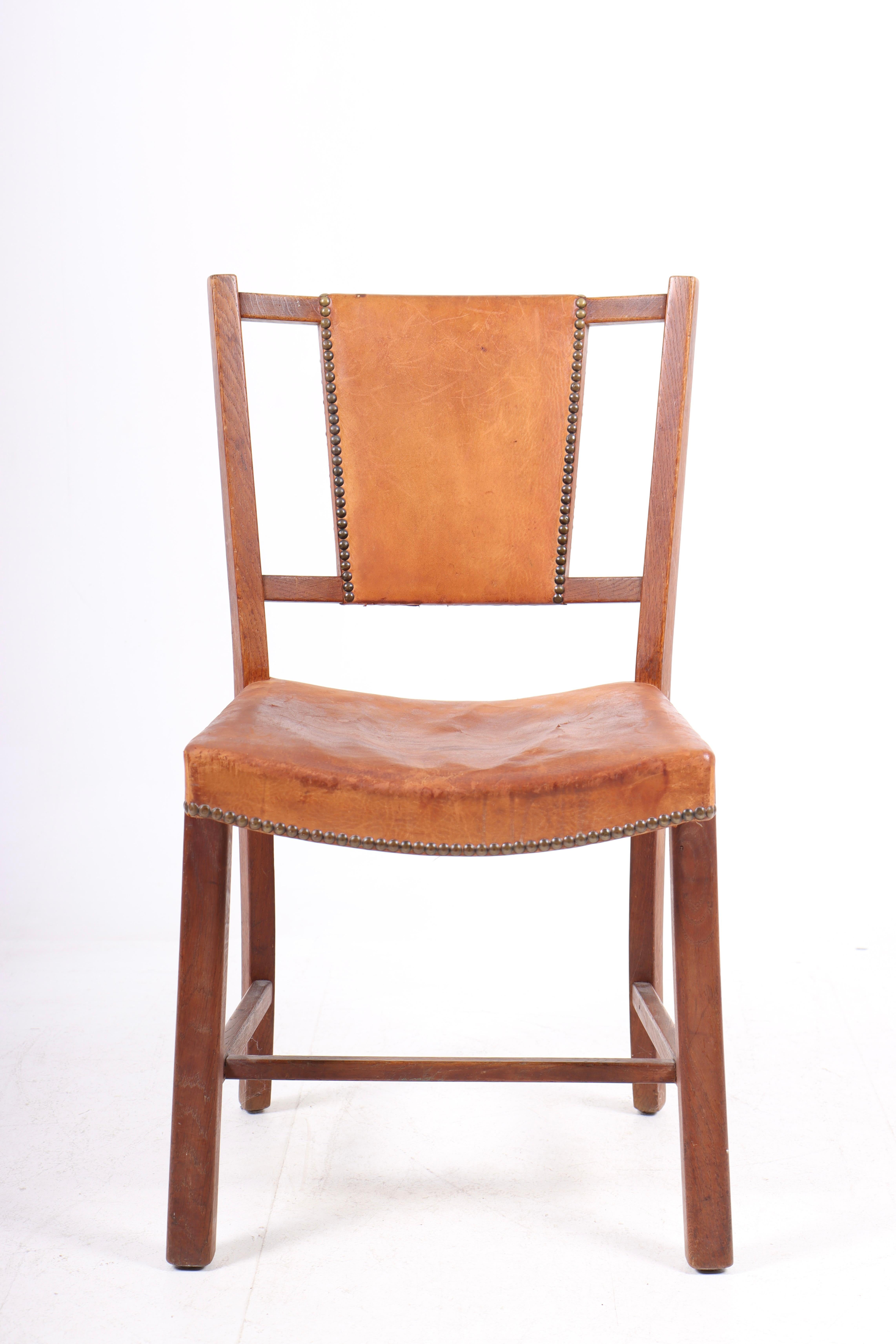 Danish side chair in patinated leather and oak. Designed and made in Denmark, original condition.