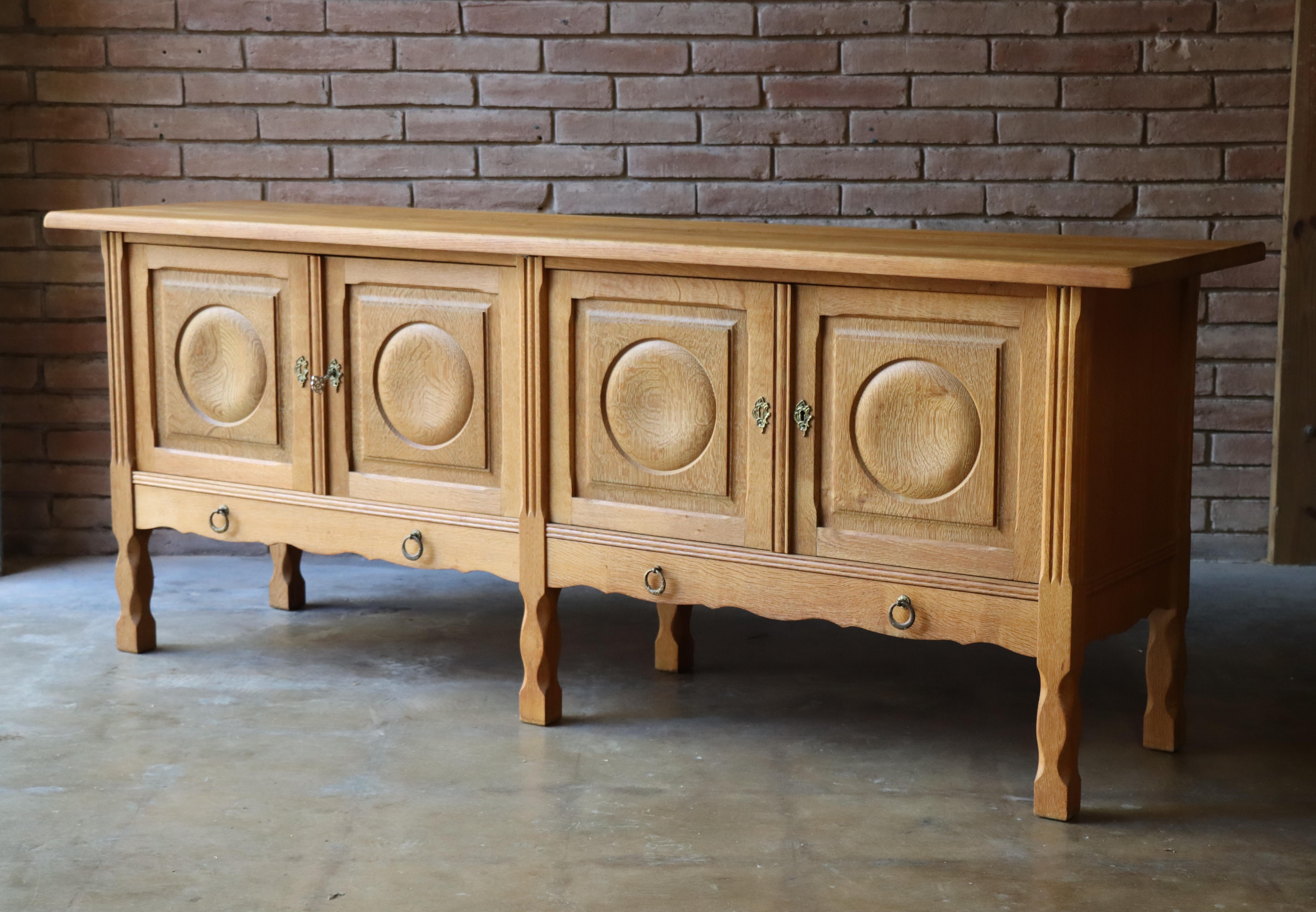 Danish sideboard attributed to Henry (Henning) Kjaernulf, c. 1960s. Handcrafted from completely solid quarter-sawn oak, this statement cabinet offers ample storage and looks good while doing it. 

Each cabinet door opens to reveal a solid oak