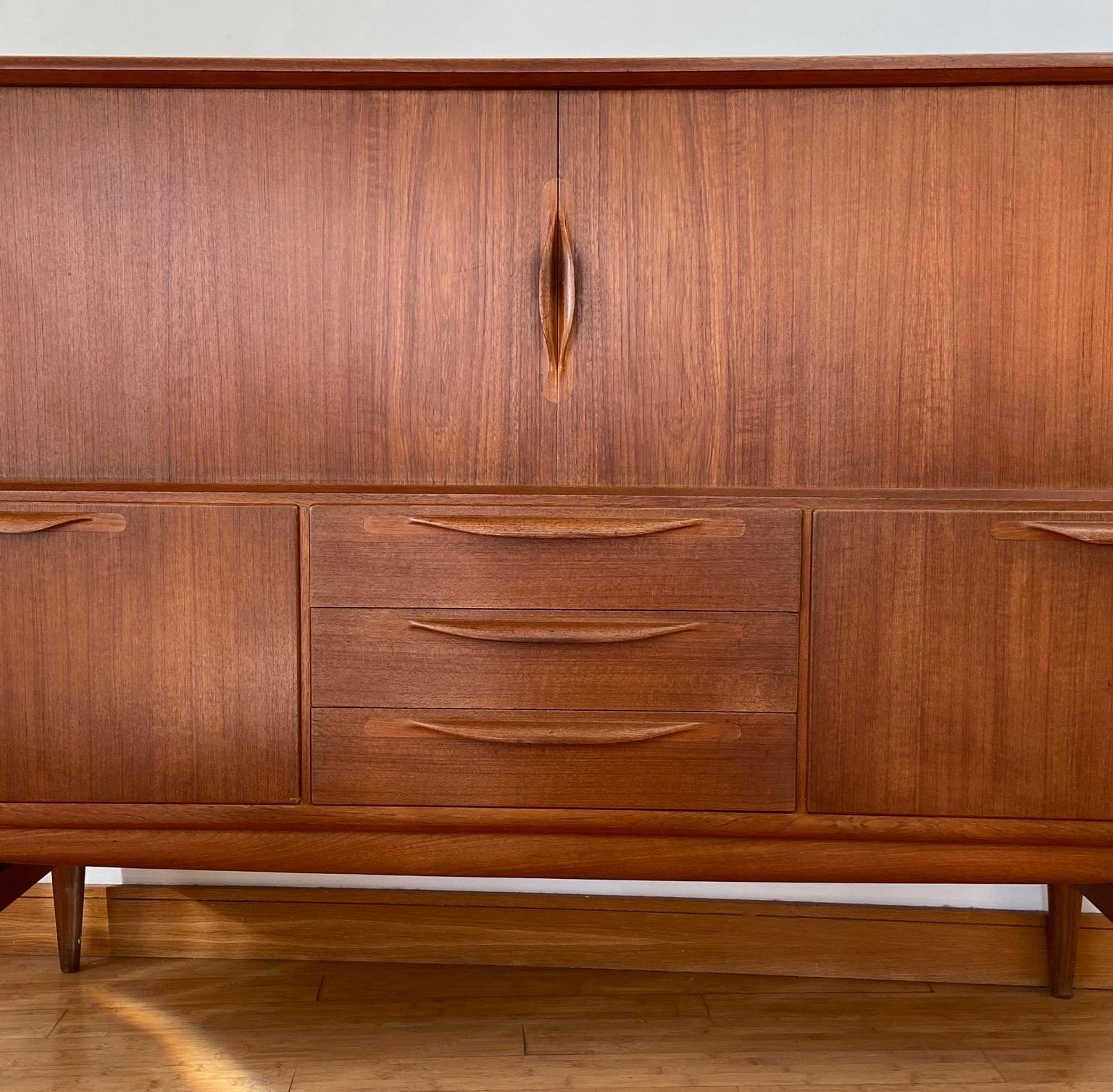 Impressive design sideboard in teak; with two sliding doors on the upper part, three drawers in the middle and two flap doors on the right and left lower hand side.