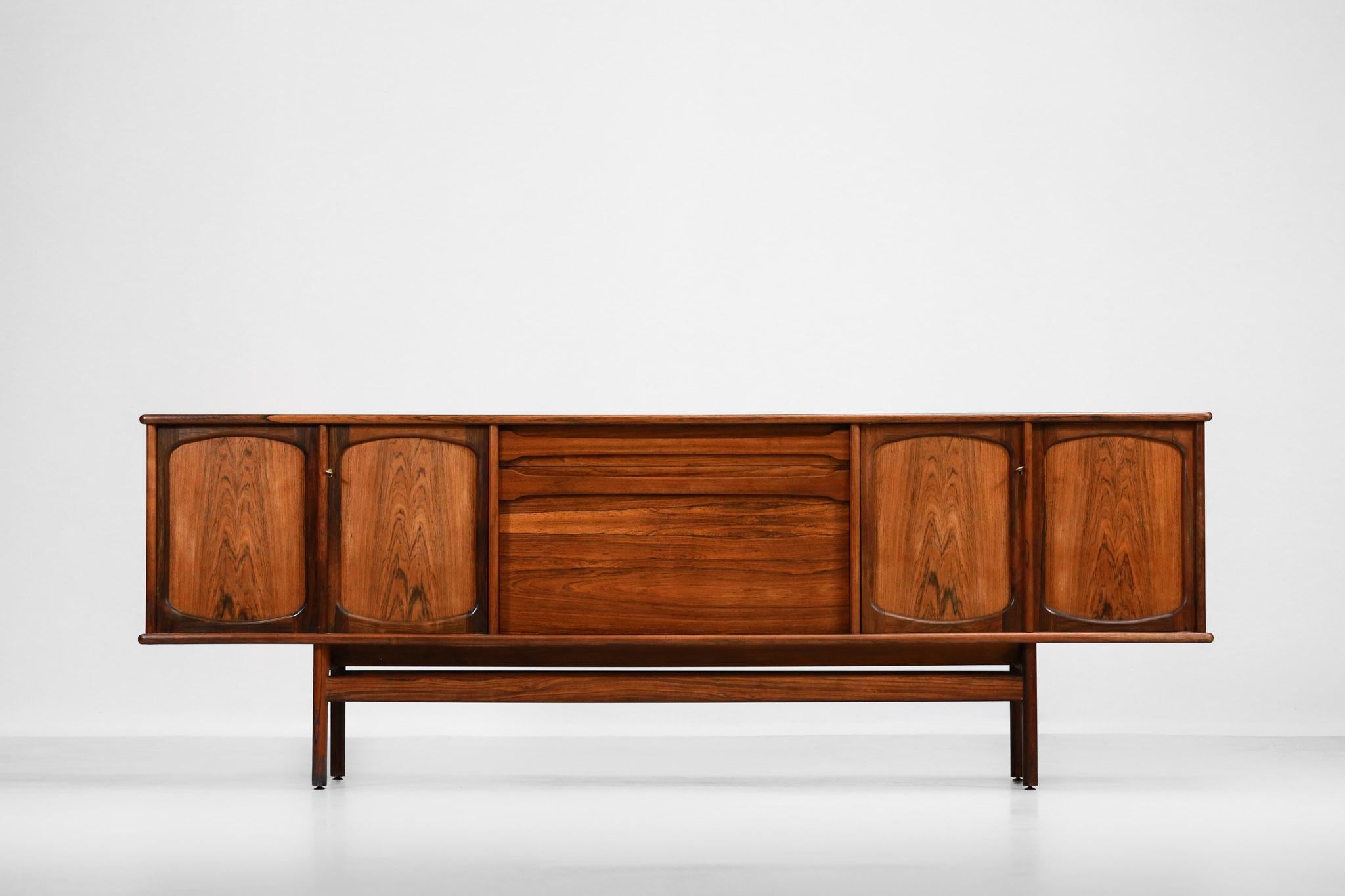 Danish sideboard from the 1960s designed by the Norwegian designer Gerhard Berg.
Structure in solid rosewood and veneered.
It is composed of four sliding doors and a central drawer overhanging a swing door opening onto a bar (keys supplied).
The
