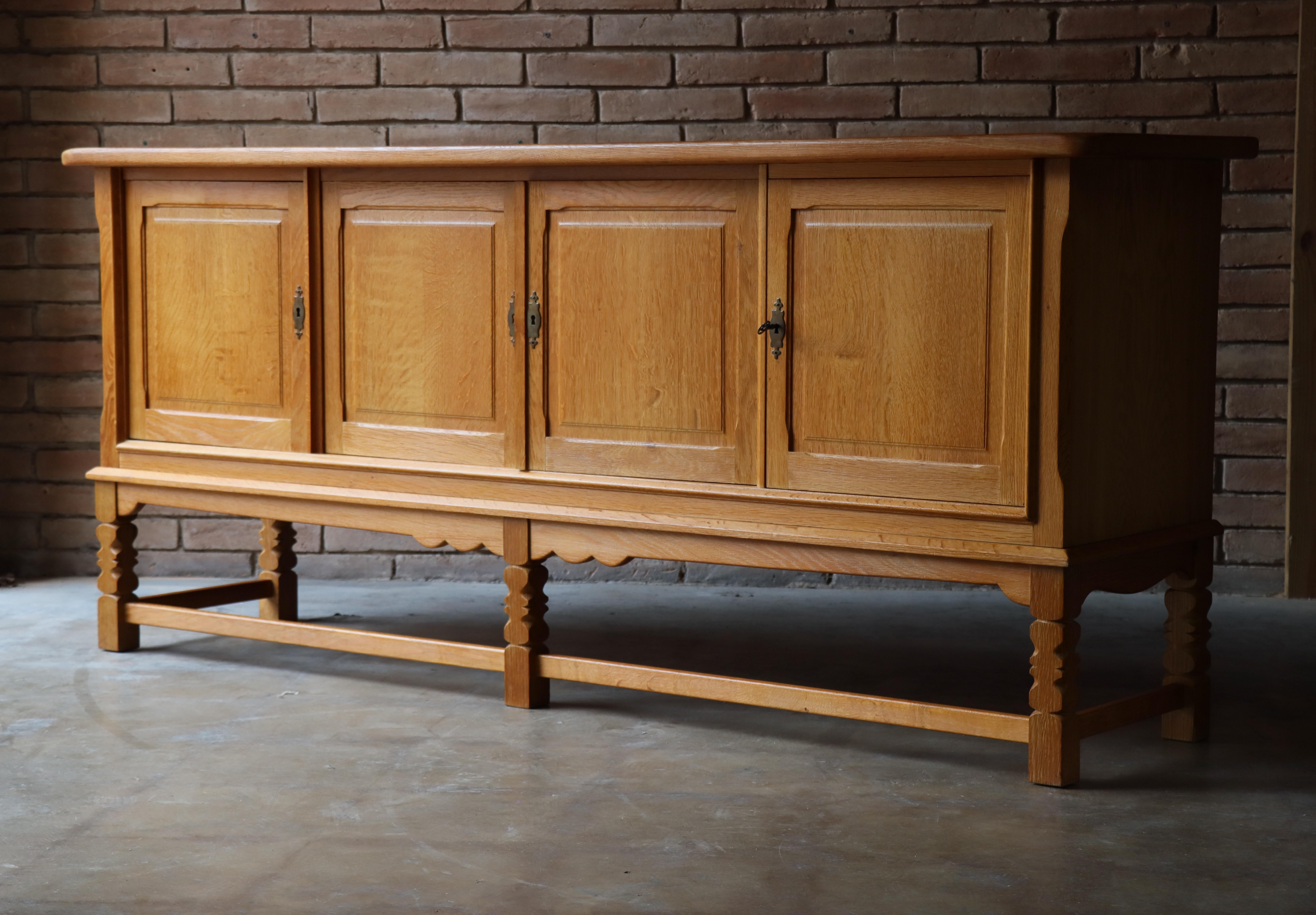 Danish sideboard by Henry (Henning) Kjaernulf. Handcrafted from completely solid quarter-sawn oak, this statement cabinet offers ample storage and focus on functionality. Each opens to reveal a solid oak interior with adjustable shelving and three