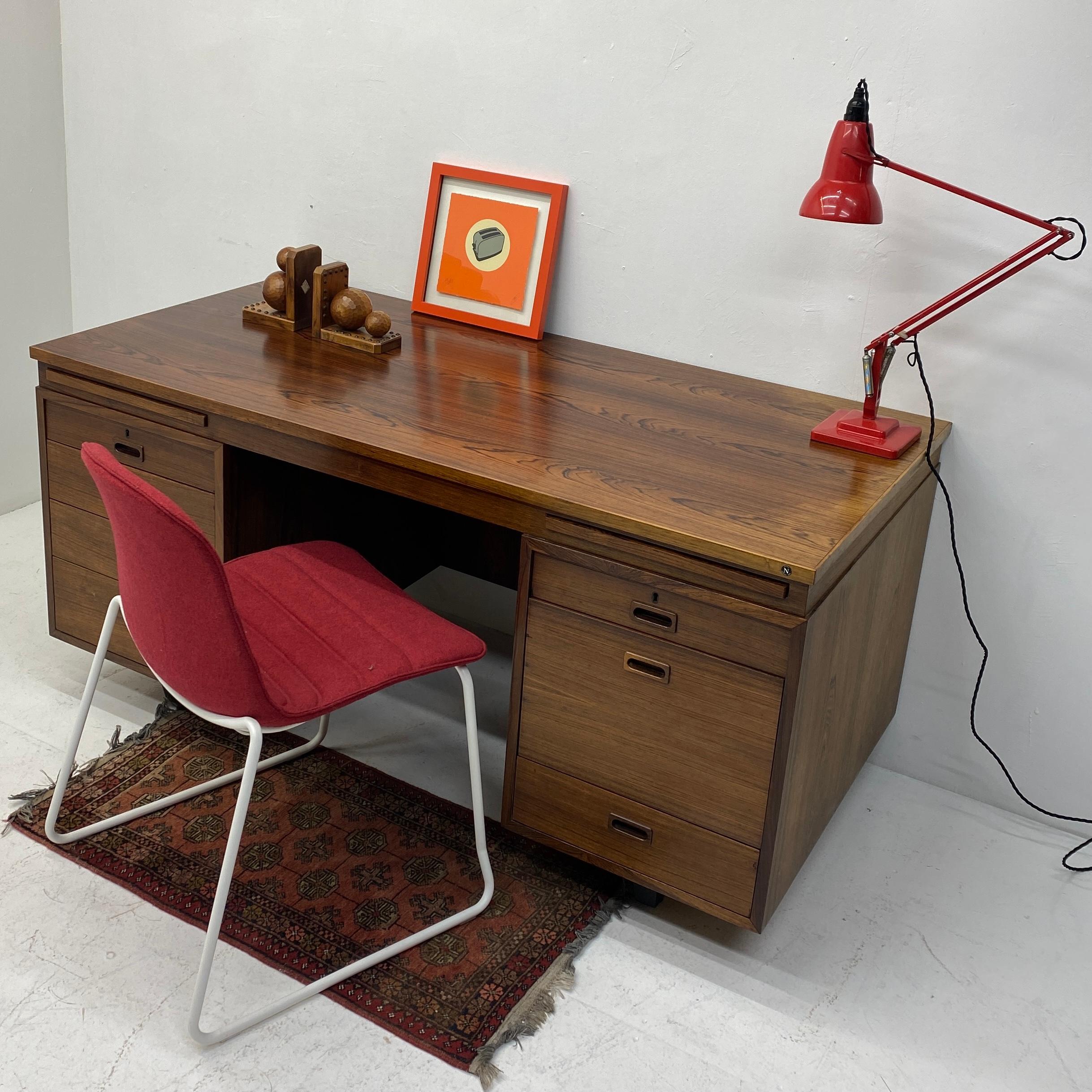 A stunning midcentury Brazilian rosewood executive desk. The desk is designed by Danish Sigvard Bernadotte. It is constructed from solid rosewood in beautiful tones & grain. It oozes quality. The desk has two desk tidy pullouts for stationary, seven