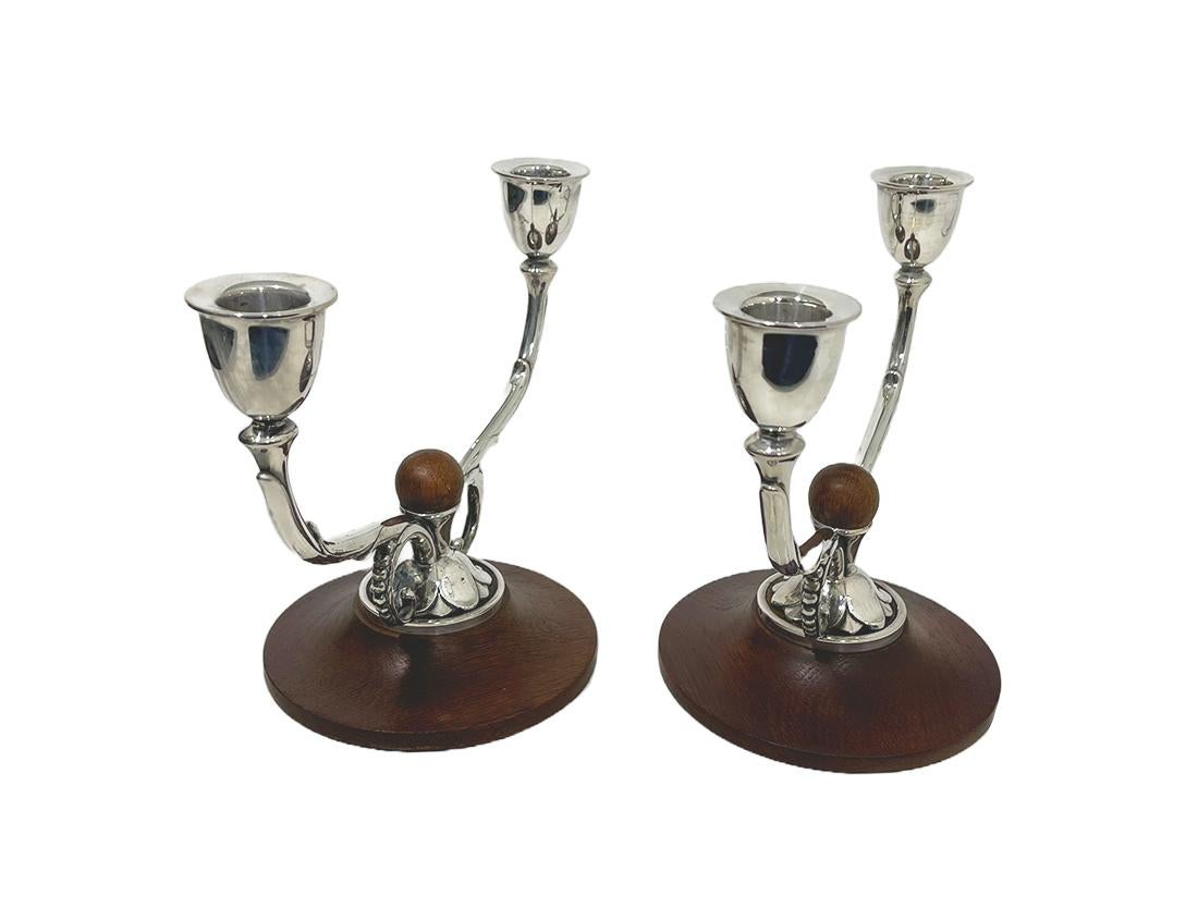 Danish silver two light candelabras, by A. Dragsted for Johannes Siggaard, 1943.

Two candelabras with each 2 arms, raised on a teak wooden round base decorated with curl and leaf pattern and in the middle a round teak wooden ball. Very light in