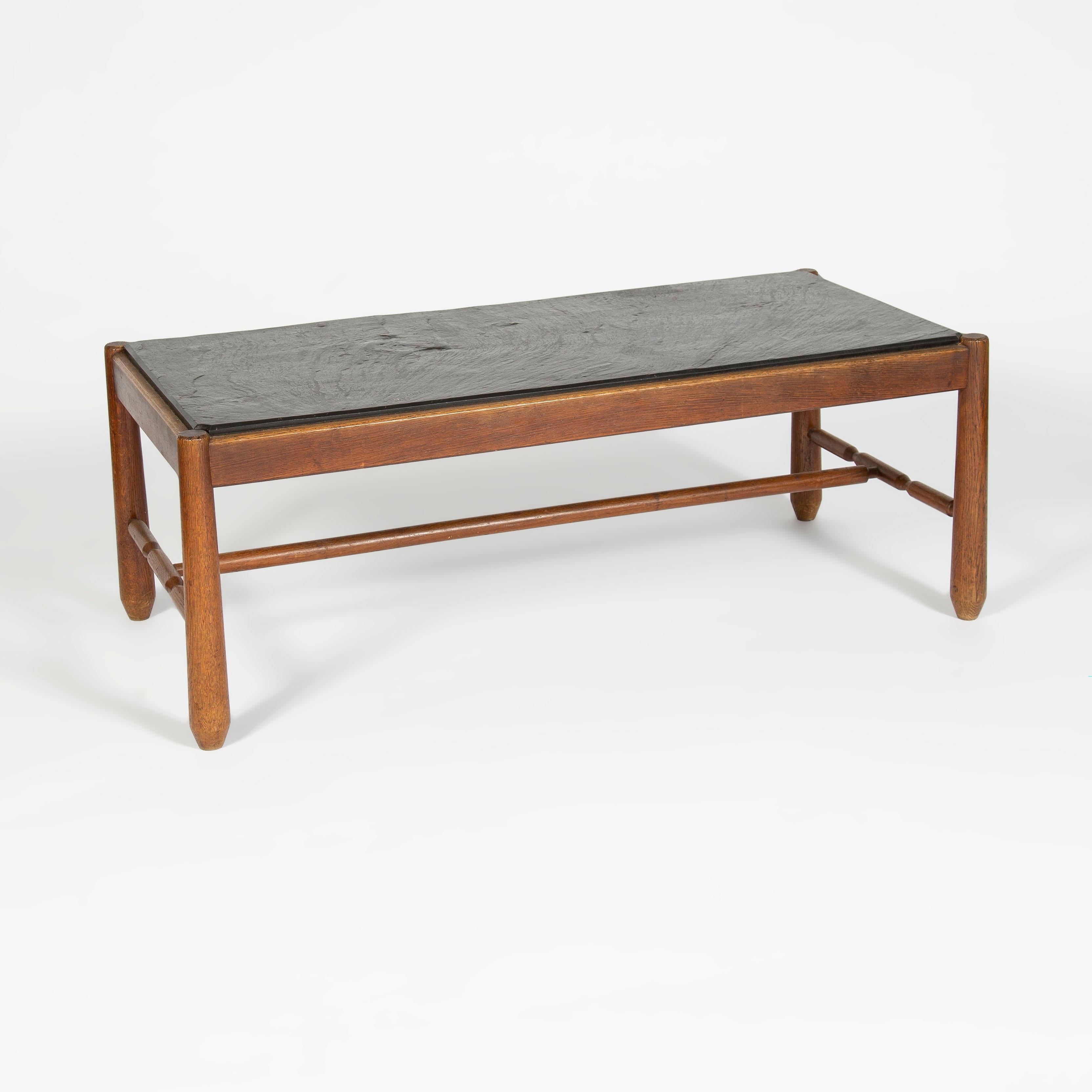 Rectangular coffee table with a rectangular teak frame with notch cut details. The top is made from a solid piece of dark color slate set in to the framework.