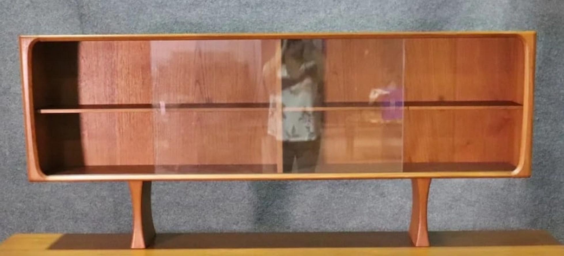 Mid-century modern low cabinet with two sliding glass doors. The frame is made of teak wood and makes for a sleek TV console or dry bar.
Please confirm location NY or NJ