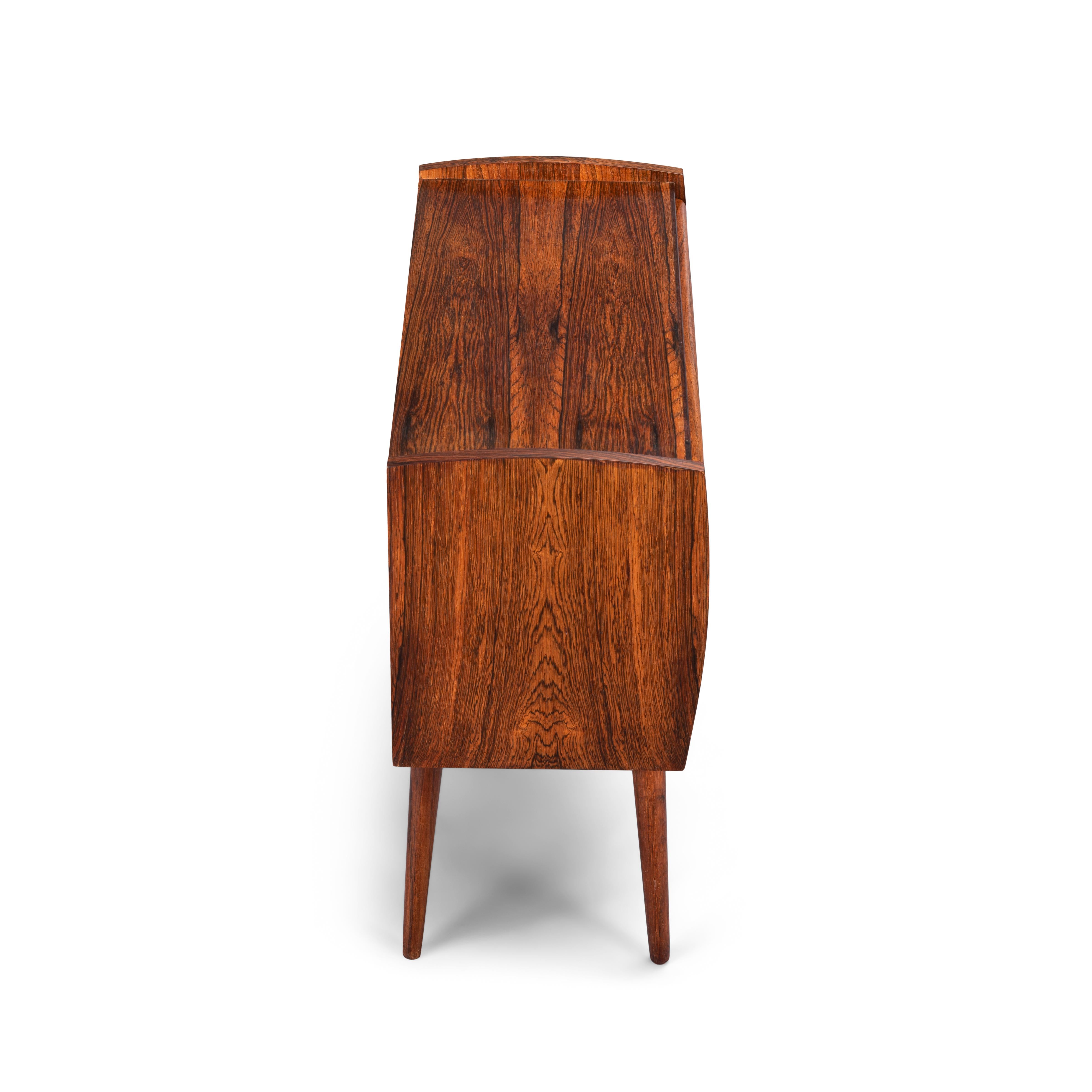 This Danish nightstand in gorgeous hardwood vineer was made late 1960s and looks very charming on its tall solid hardwood legs. Three drawers with a solid wooden grip attached onto the middle of each drawer makes the style of this nightstand