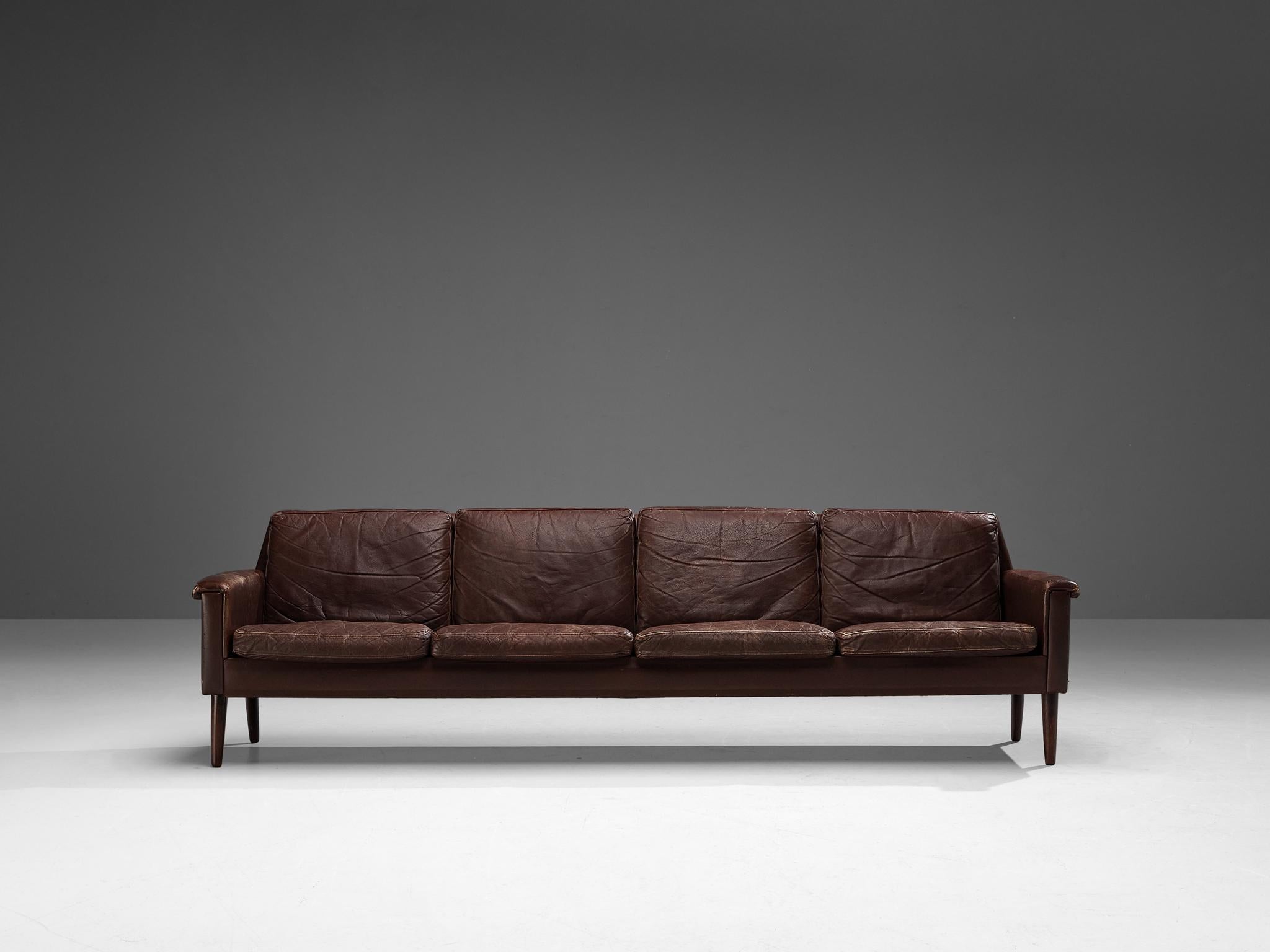 Sofa, leather, teak, Denmark, 1960s

This classic sofa of Danish origin features modest and subtle lines and angular shapes that emphasize the clear construction of the design. The armrests curl gently over the armrests, resulting in an elegant