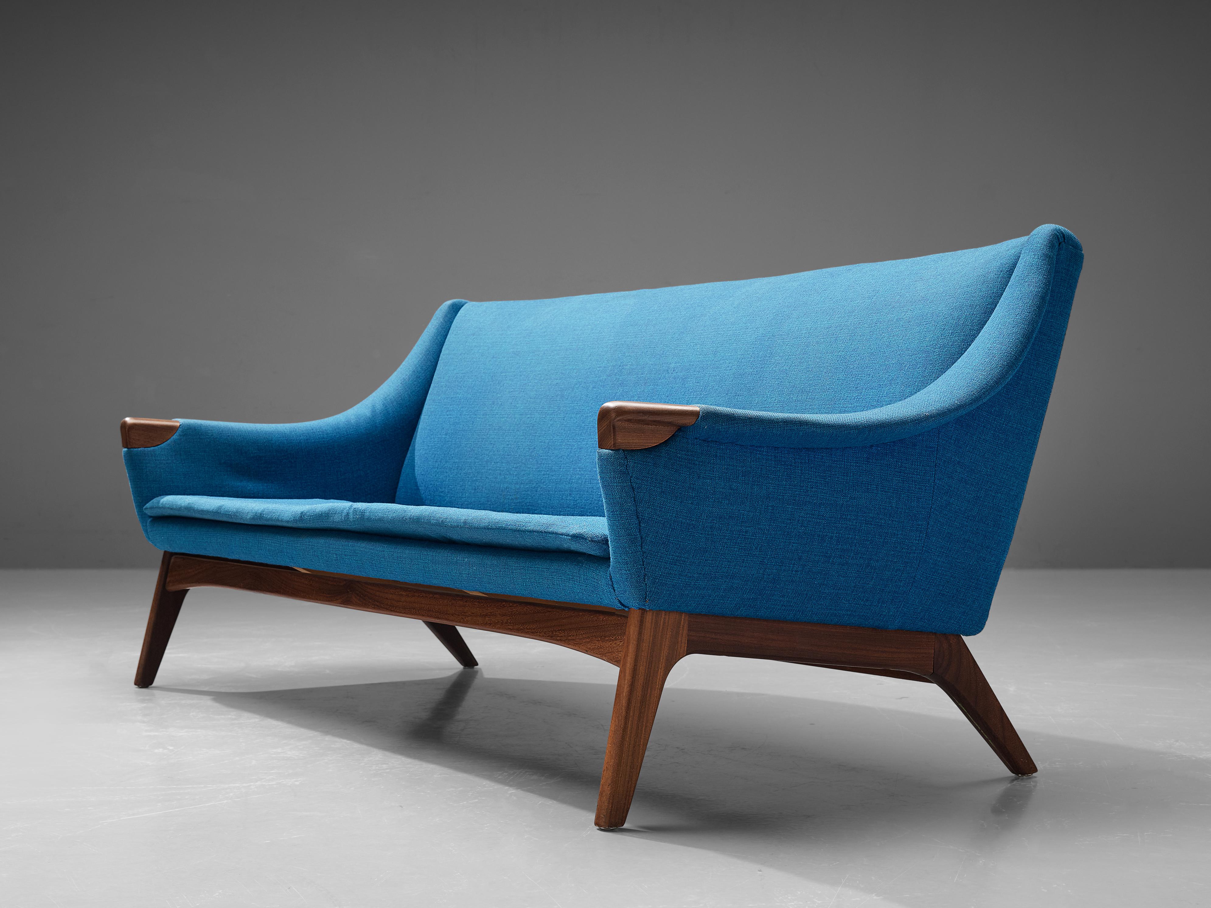 Danish sofa, teak, fabric, Denmark, 1960s 
 
This three seater sofa features a refined blue fabric upholstery and the elegantly executed tapered legs are made out of teak. A remarkable detail are the revealing teak ends of the armrests, creating a