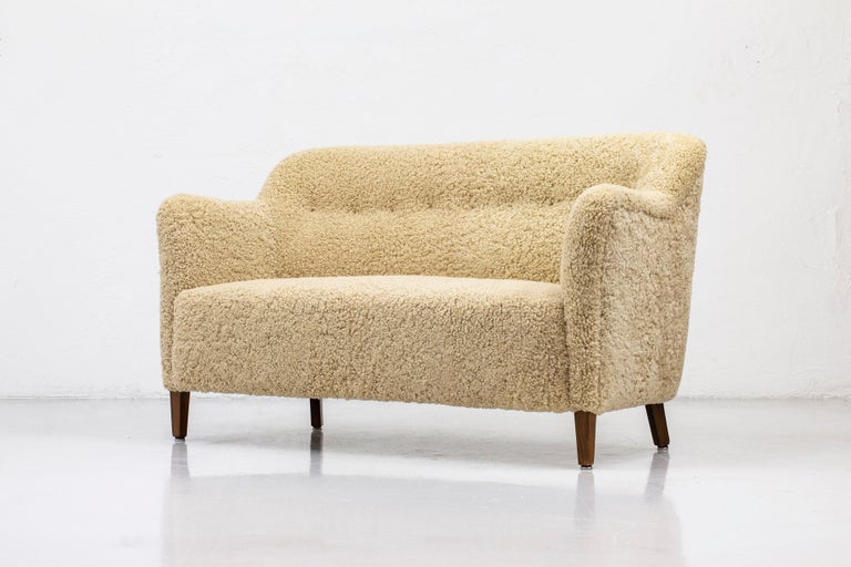 Two seater sofa made by cabinetmaker Edmund Jørgensen. Produced in Denmark during the 1940-50s. Dark stained oak legs and new sheepskin upholstery in light beige color. Very good vintage condition with few signs of patina from age and