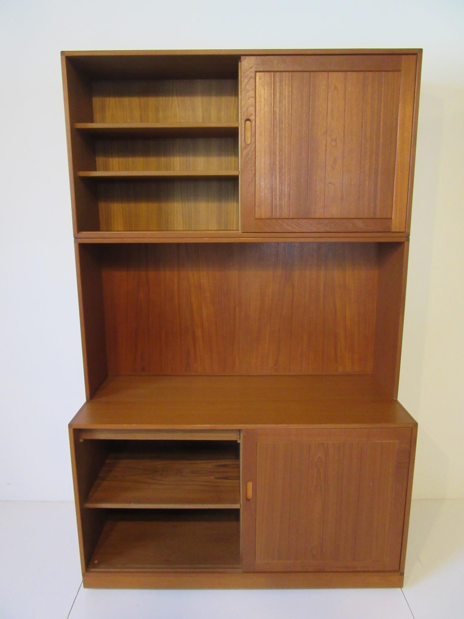 A well crafted 3-piece cabinet or bookcase with grooved panel sliding doors that has fine leather inside the finger pulls, adjustable shelves and the lower cabinet having a small drawer. This solid teak constructed cabinet was bought in Denmark in