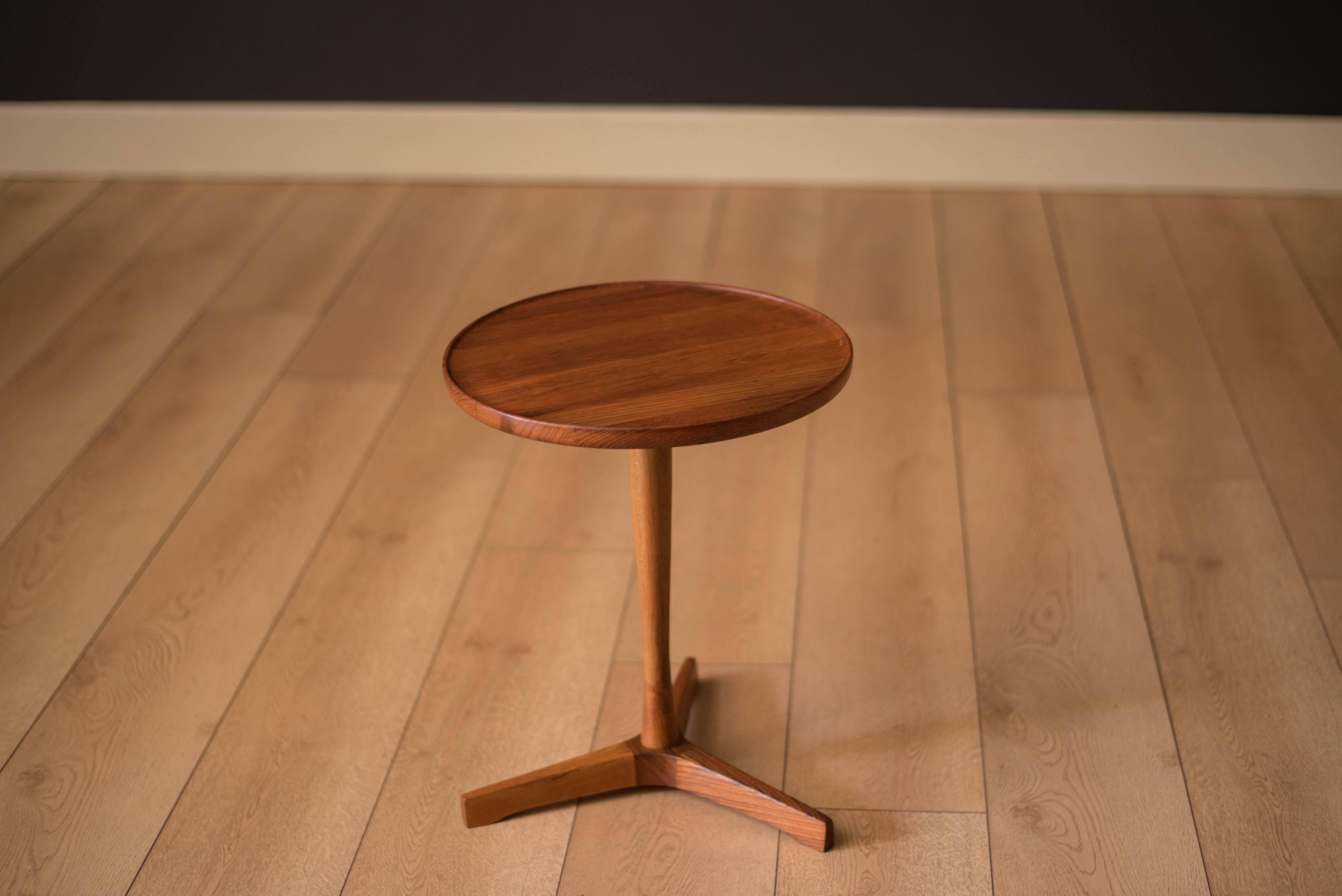 Mid century modern round side table designed by Hans C. Andersen for Artex, Denmark. Features a solid planked teak table top with a raised edge supported by a pedestal base.