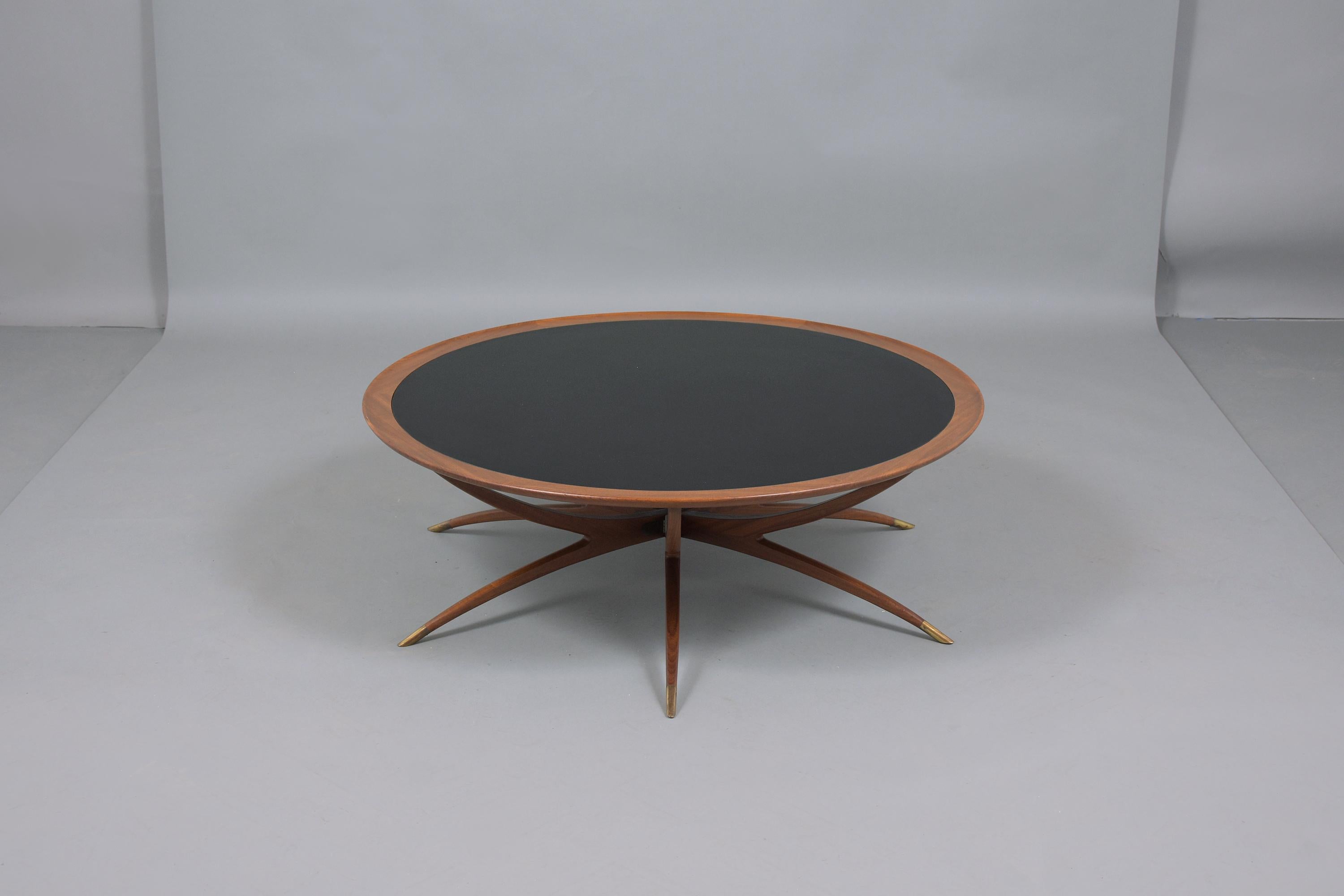 This mid-century danish spider leg coffee table is made in the style of Carlo di Carli, crafted out of solid wood, and professionally restored by our team of in-house craftsmen. The table comes with black tinted glass in good condition, its natural