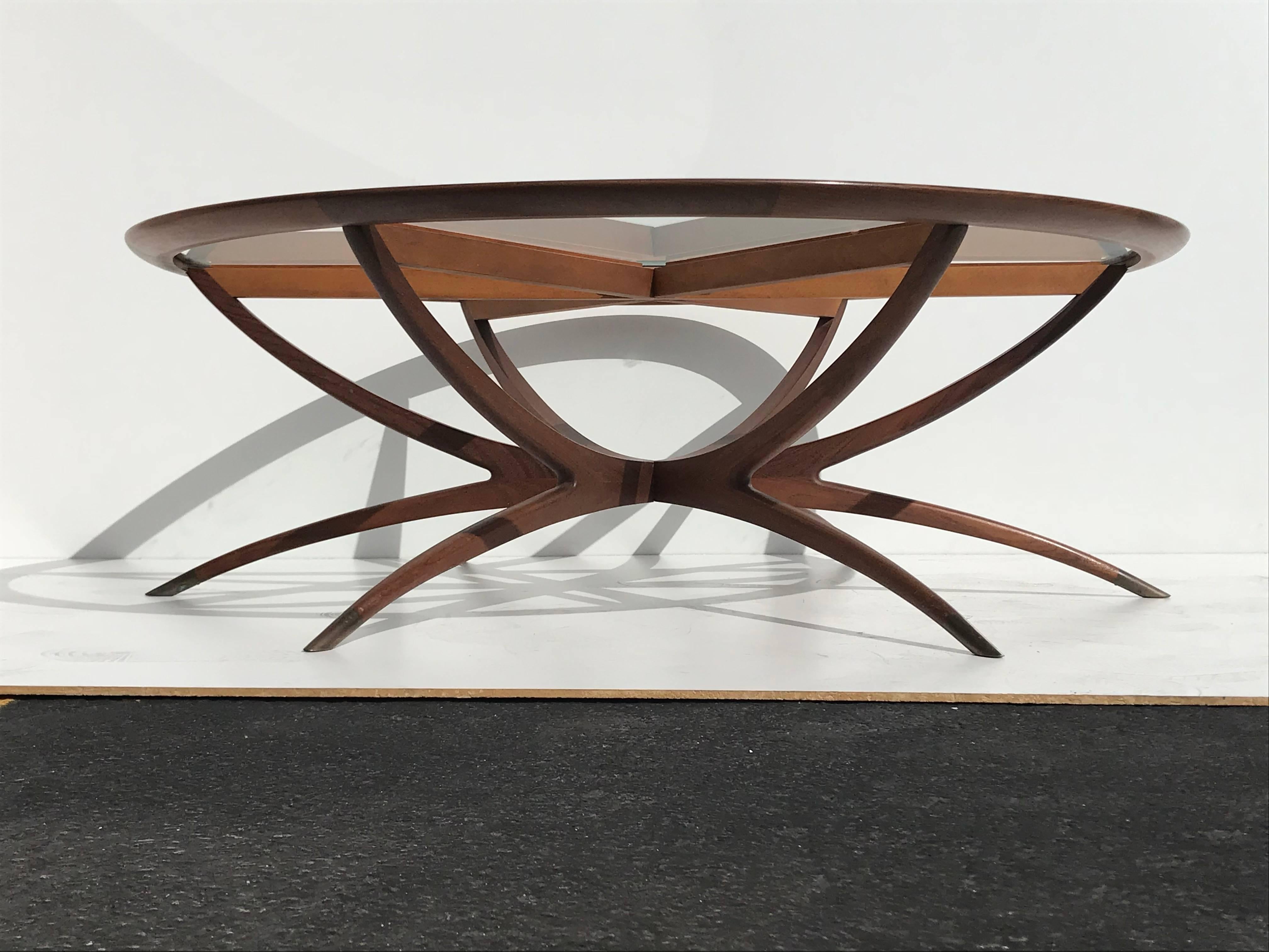 Midcentury Danish spider leg coffee table in the style of Carlo di Carli. Made of hard tropical teak wood and patinated brass sabot legs which can be polished at customers request. Base is detachable and folds for easy storage and moving.

Offered