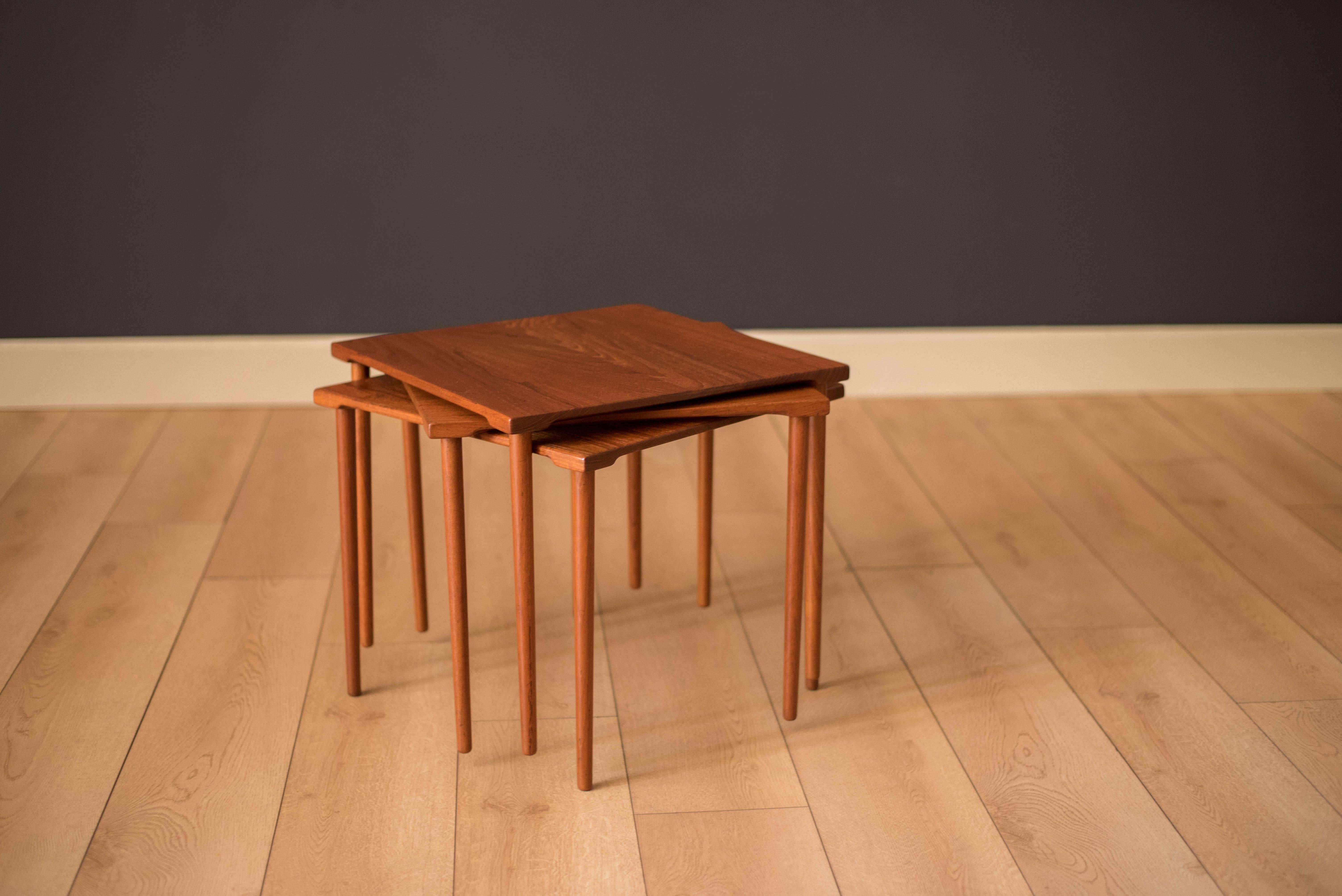 Early mid century set of stacking side tables manufactured by France & Daverkosen, Denmark. Table tops are constructed of solid planked teak with classic slender dowel legs. This set can be used as a coffee table or separate as three end tables.