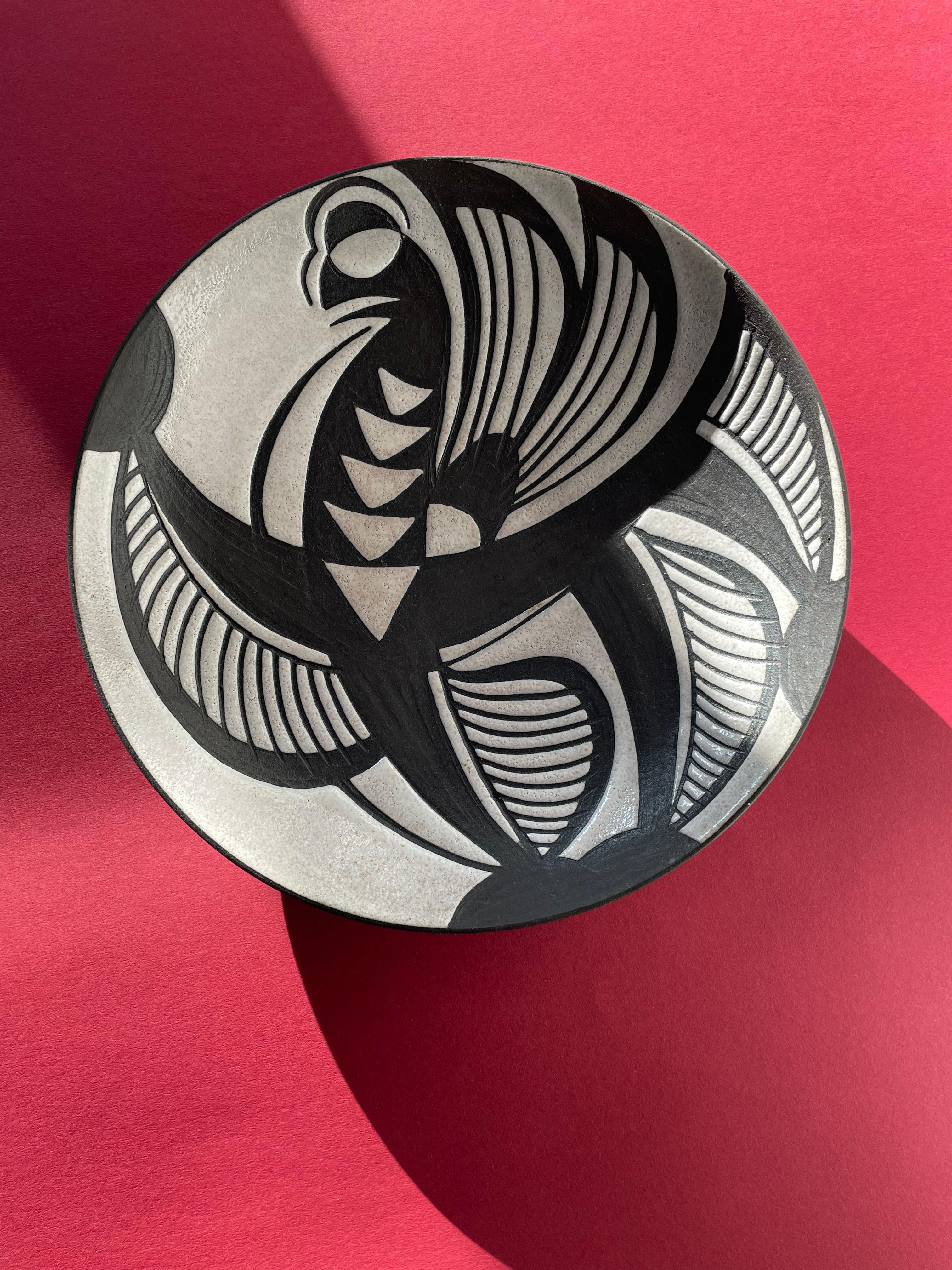 Danish modernist decorative plate / wall decoration / centerpiece with strong graphic decor from the Tribal Harlekin series by ceramic artist Marianne Starck (1931-2007). Shiny bone white glaze with hand-carved graphic lines in raw anthracite