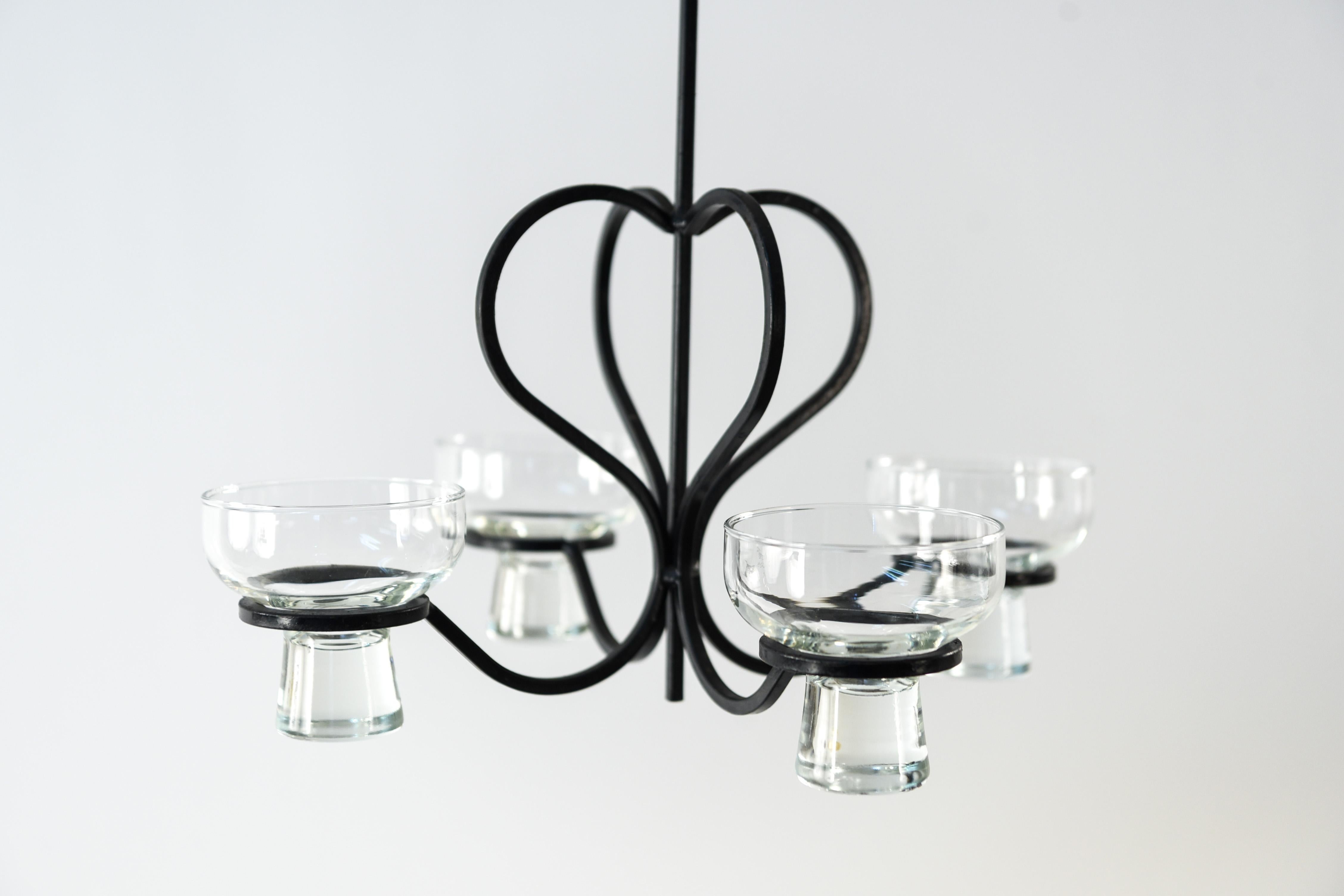 This Danish chandelier from the 1970s has a curvy steel frame with glass inserts to hold candles. This piece has a simple charm to it with its lovely lines and details.