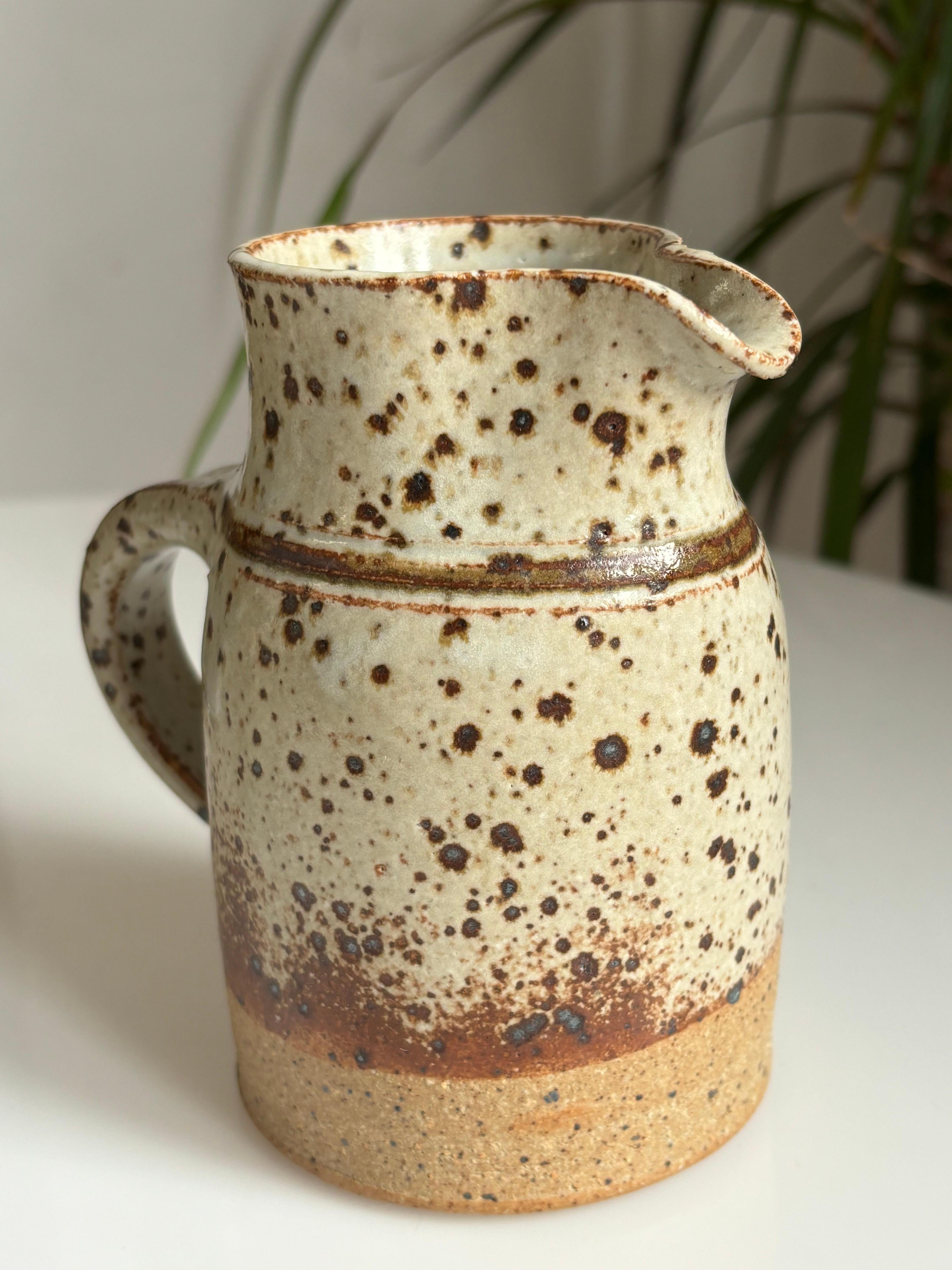 Japanese inspired Danish modern vintage stoneware pitcher to be used as serveware or as a vase. Stunning earthcolored spotted glaze over the handmade soft organic shape with spout and handle. Manufactured by ceramic artist Ejnar Paulsen on the