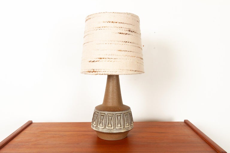 Danish stoneware table lamp by Helge Bjufstrøm for Michael Andersen 1960s
Danish Mid-Century Modern ceramic lamp in brown stoneware with original shade. Geometric tribal pattern in cream colored glaze. 
Made on the Danish island of Bornholm by the
