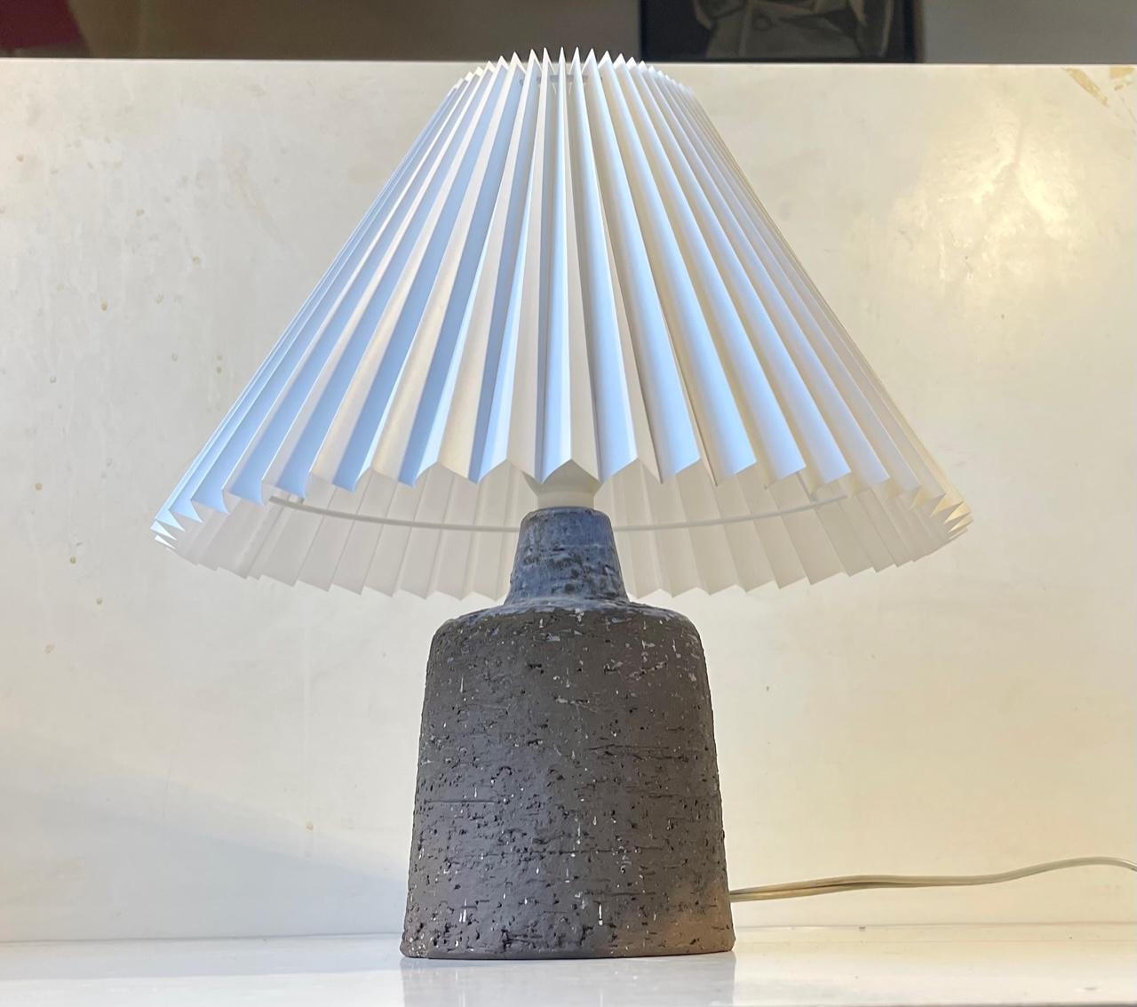 Stylish mallet shaped stoneware table lamp with fluted white Danish shade. The base exhibits a delicate light-purple glaze and an incised cubist motif. Designed and made in Denmark circa 1970. Measurements: height: 35 cm, diameter: 30 cm (shade).