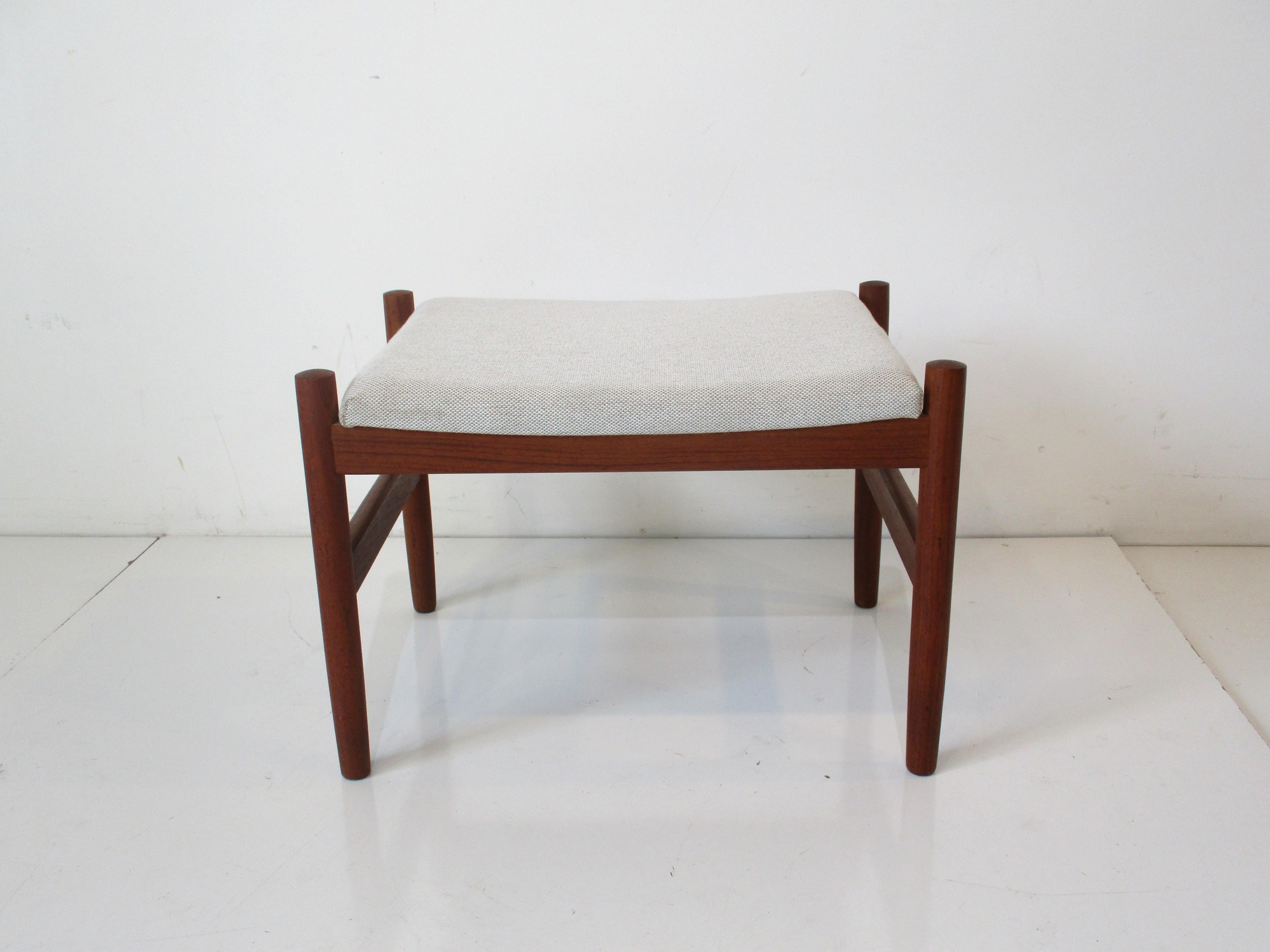 A smaller sized teak wood framed ottoman or stool with an upholstered cushion designed by Hugo Frandsen for Spottrup Mobler Denmark. Great piece to acompany a lounge chair or just used as a stool.