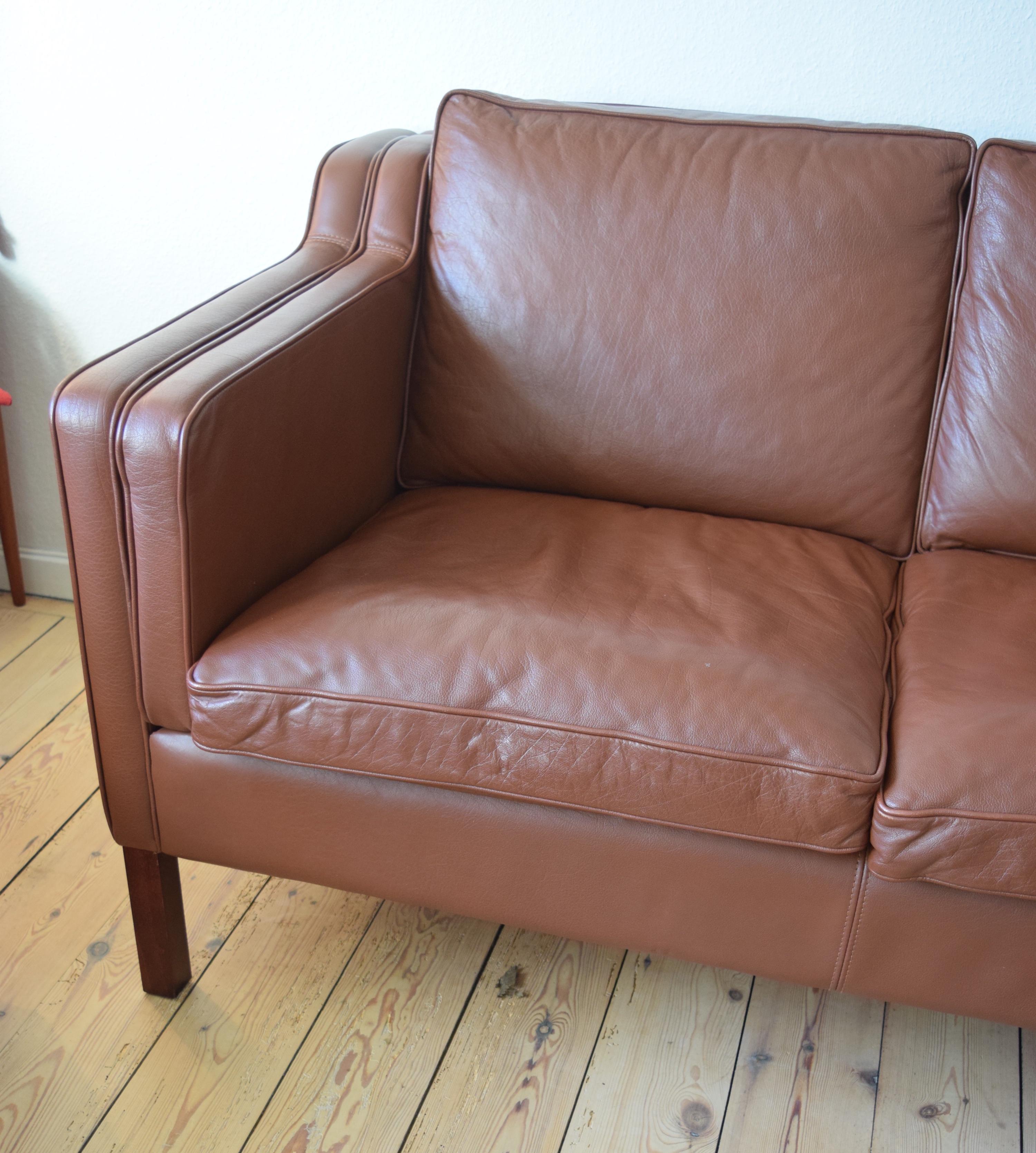 Scandinavian modern sofa 3-person tan leather sofa. This sofa is covered in beautifully grained leather and sits on square mahogany legs. This sofa sat for many years in a Danish summer-house and shows very little wear for its age. Based on the 2213