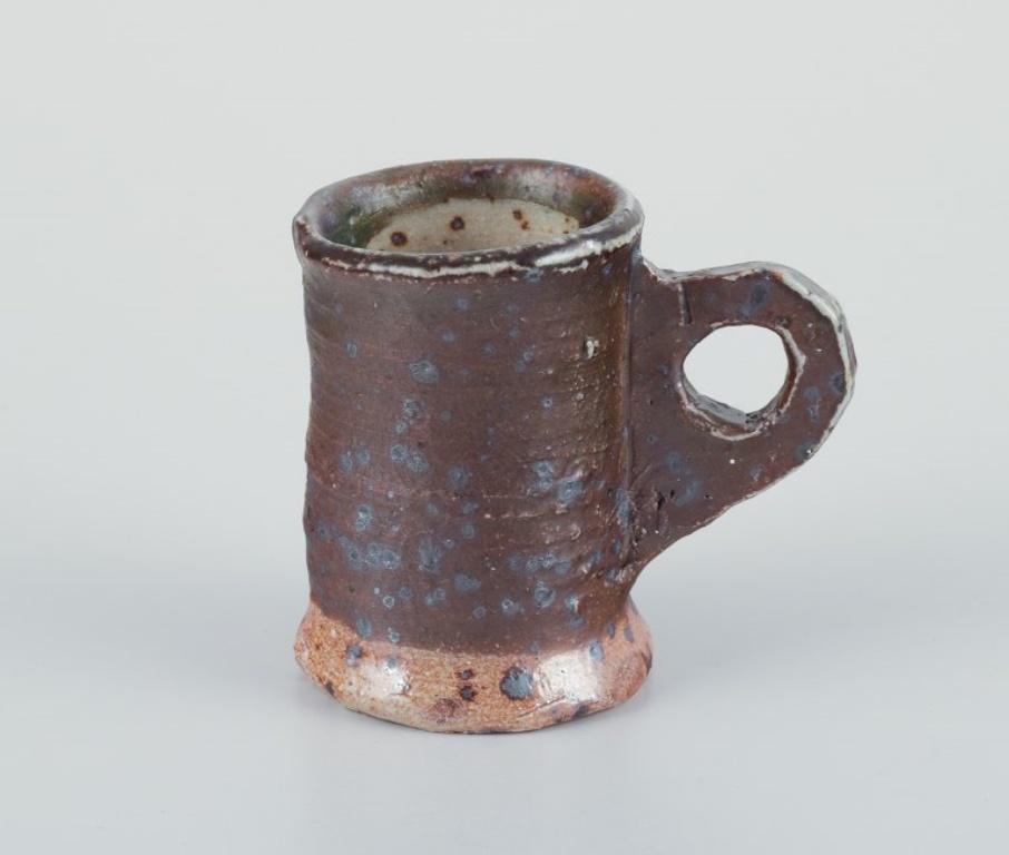 Danish studio ceramicist.
Three unique miniature ceramic mugs.
Decorated with various earth-toned glazes.
1970s/1980s.
Signed and marked.
In perfect condition. 
Brown one: Diameter 4.0 cm without handle x Height 5.5 cm.
