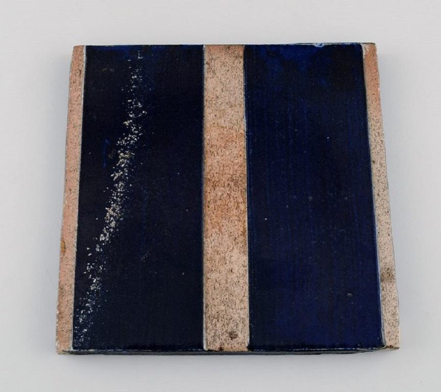 Danish studio ceramicist. Two unique tiles in glazed stoneware. 
Patterned decoration in dark blue, green and sand shades. Late 20th century.
Largest measures: 17 x 17 cm.
In excellent condition.
