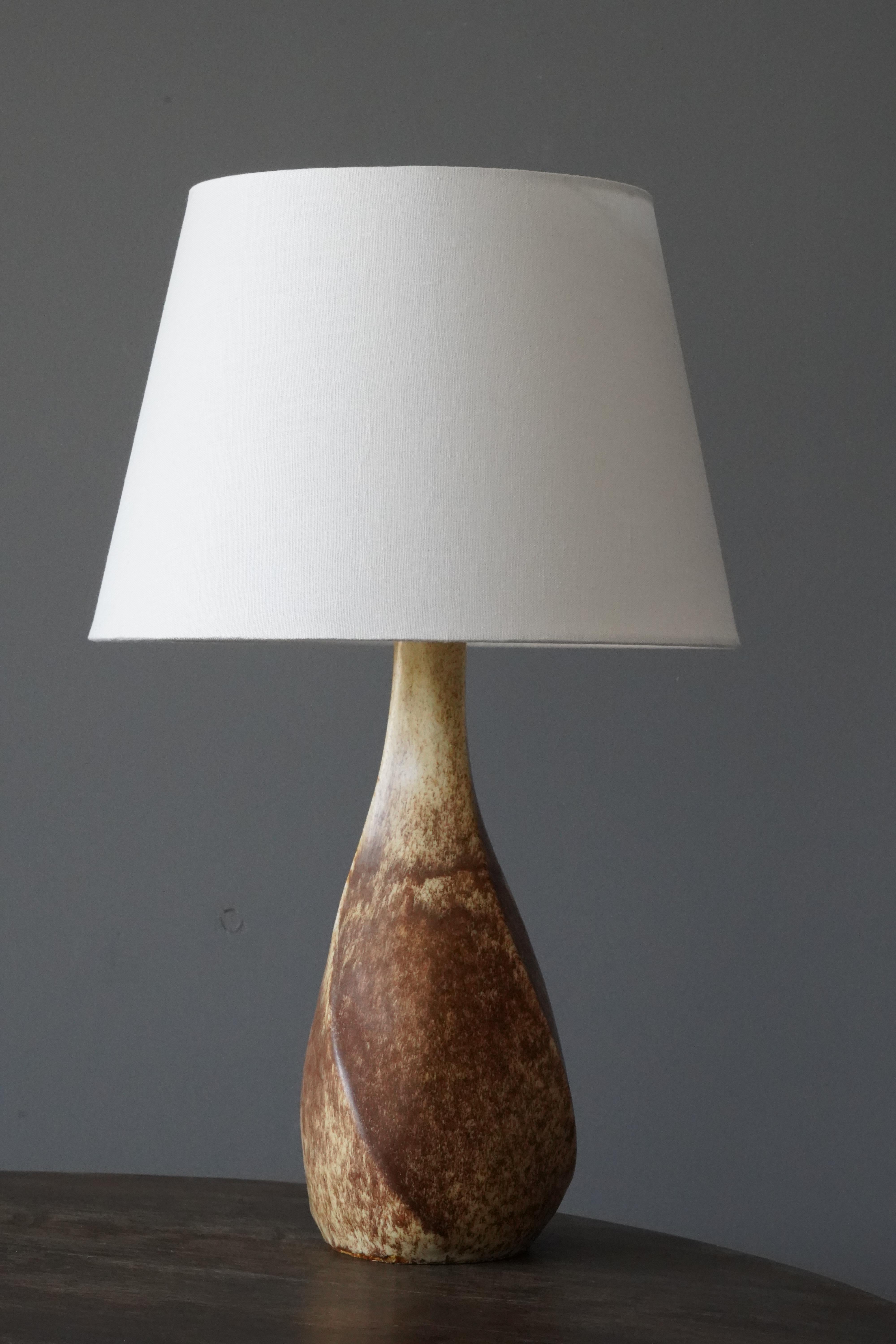 A sizable table lamp. In glazed stoneware. Signed to bottom.

Stated dimensions exclude lampshade. Height includes socket. Sold without lampshade.

Glaze features brown-beige colors.