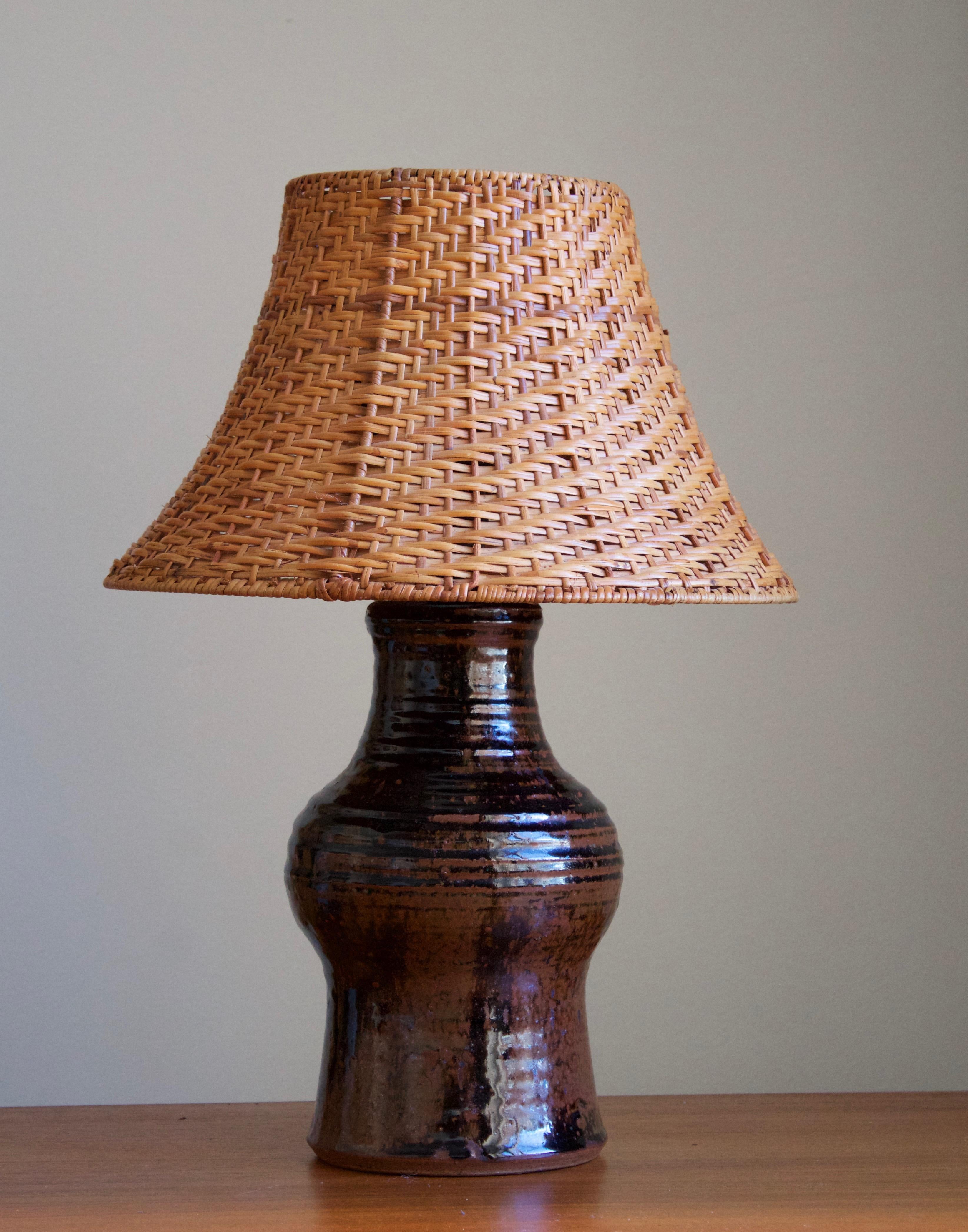 A sizable table lamp. In glazed ceramic, either stoneware or earthenware. Unsigned. 

Stated dimensions exclude lampshade. Upon request a vintage rattan lampshade of illustrated model can be included in purchase.