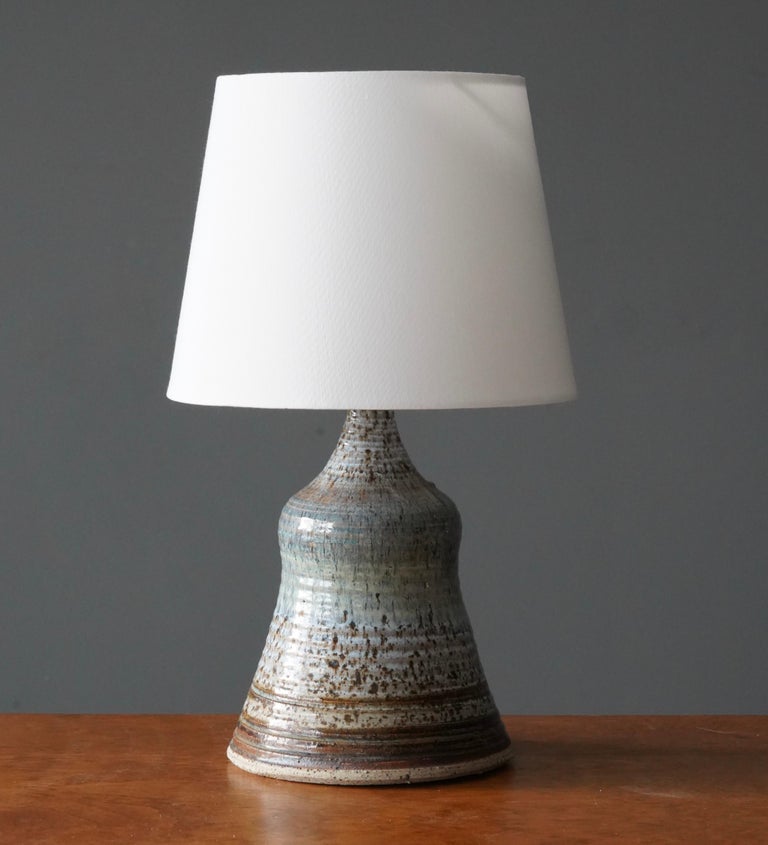 A table lamp. In glazed stoneware. Signed. In artists studio

Dimensions listed are without lampshade. 
Dimensions with shade: height is 16.75 inches, width is 10 inches.
Dimensions of shade: top diameter is 7.5 inches, bottom diameter is 10
